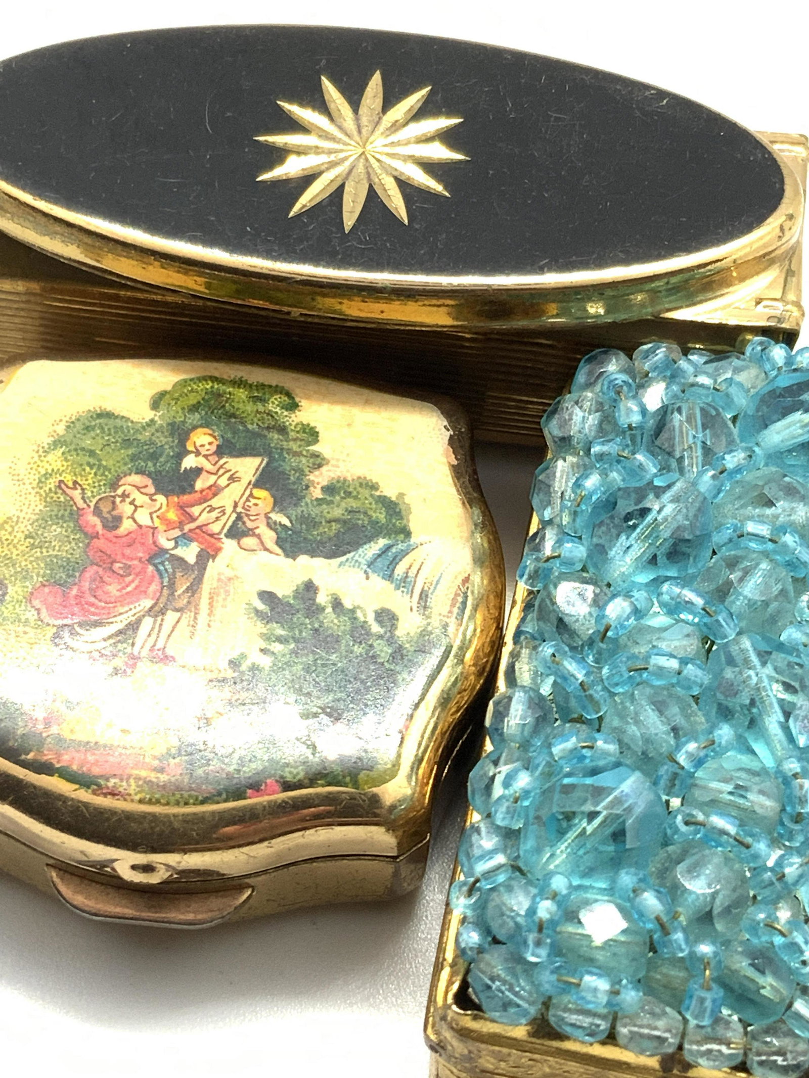Lot 3 Vntg STRATTON & More Pill And Lipstick Boxes: Three vintage gold tone metal lipstick and pill boxes. The lipstick case has an oval shaped enamel accent in relief of the lid. The center of this enamel accent is an etched, gold tone star form. Hing