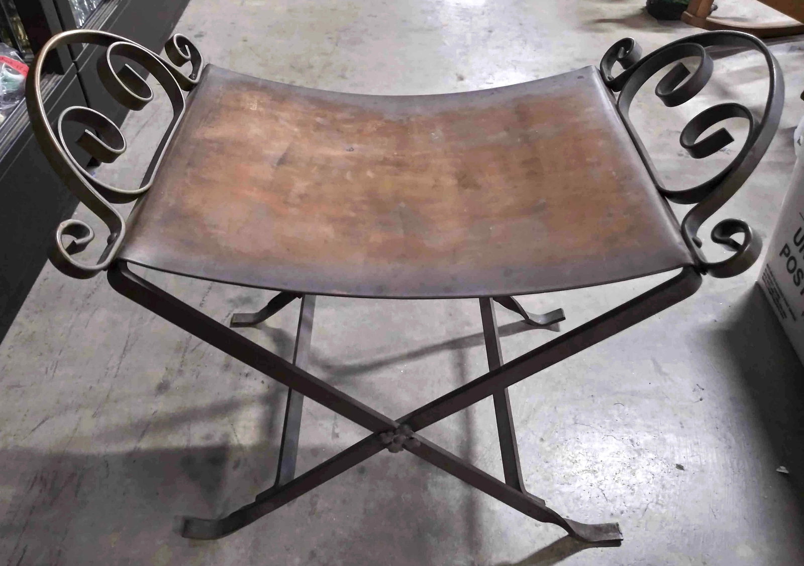 Vintage Bronze Single Seat X Bench: A vintage bronze bench meant to be a seat for one. On either end there is intricately pierced and shaped metalwork accents. Towards the center, where the joints connect, there are two etched floral ac