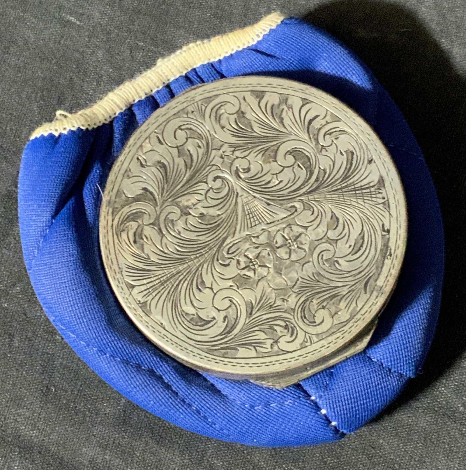 Vintage Victorian Style Silver Mirrored Compact: A vintage, possibly antique, silver compact with Victorian style etched metalwork throughout. Metalwork includes whimsical floral etchings on both sides. Snap closure. Compact opens to reveal a textil