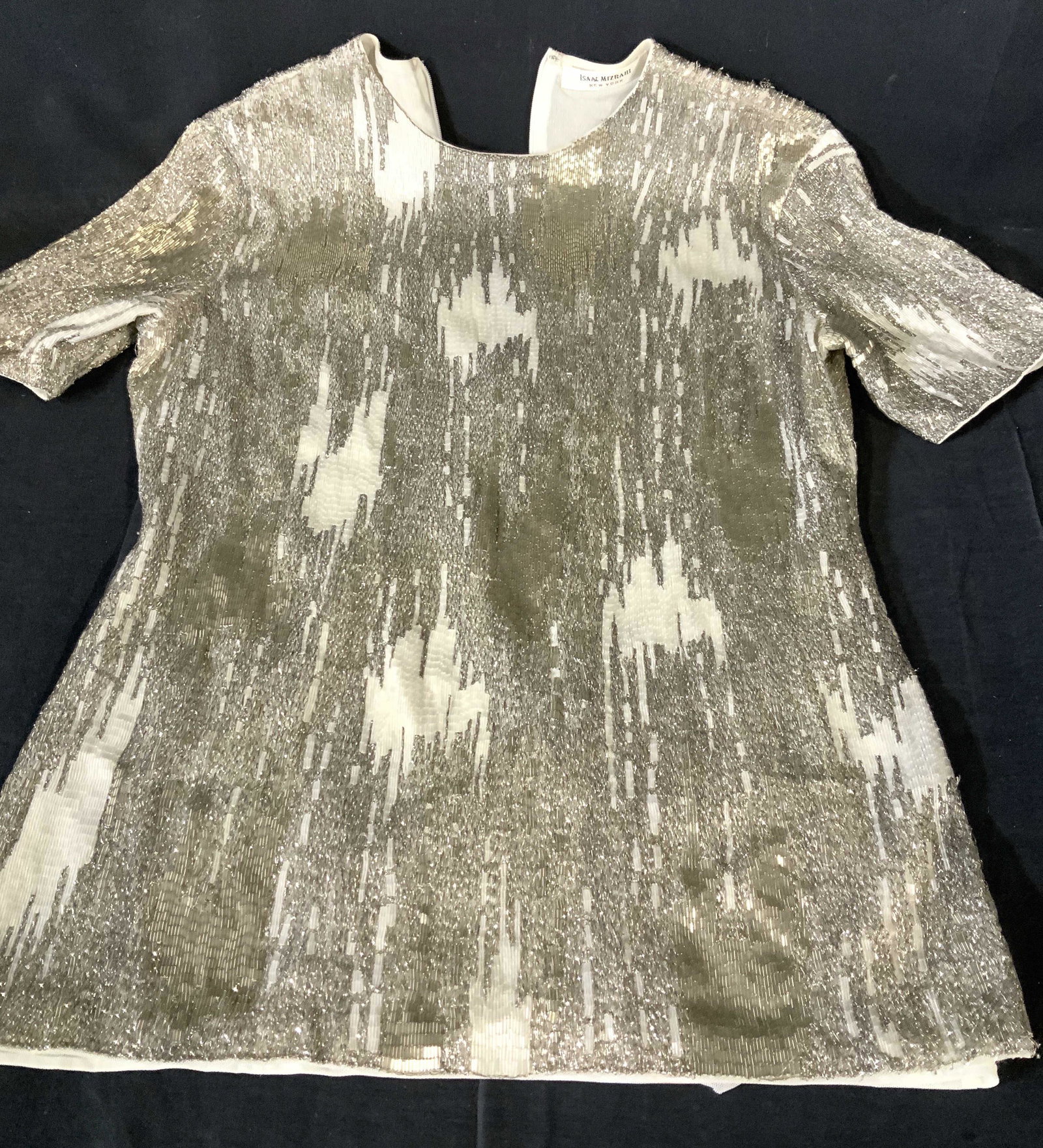 ISAAC MIZRAHI Silver Beaded Ladies Dress Top: Short Sleeve Cocktail Top, backside zipper, mesh lining, silver and white tube beading in abstract pattern, size small. 23 in long, 13 in. Chest, 28 in. Waist. Labeled Designer ISAAC MIZRAHI NEW YORK.