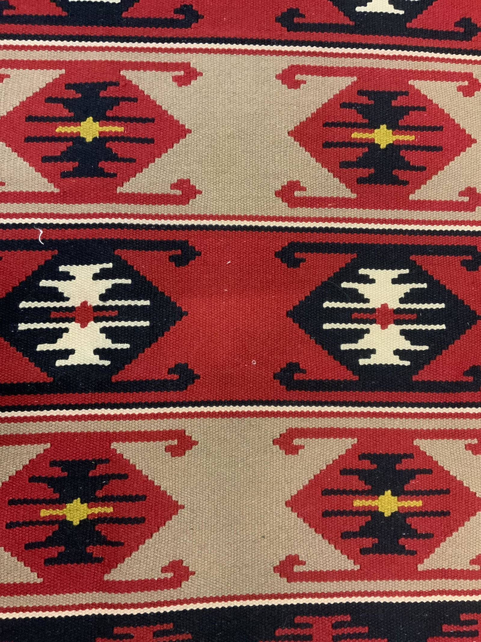 Fringed Navajo Style Area Rug: Navajo style area rug, both ends are fringed, possibly vintage. Patterns are colored in red, black, tan, and kayaking tones. Measures approx 60 inches long, and 26.25 inches W. Wear is consistent with