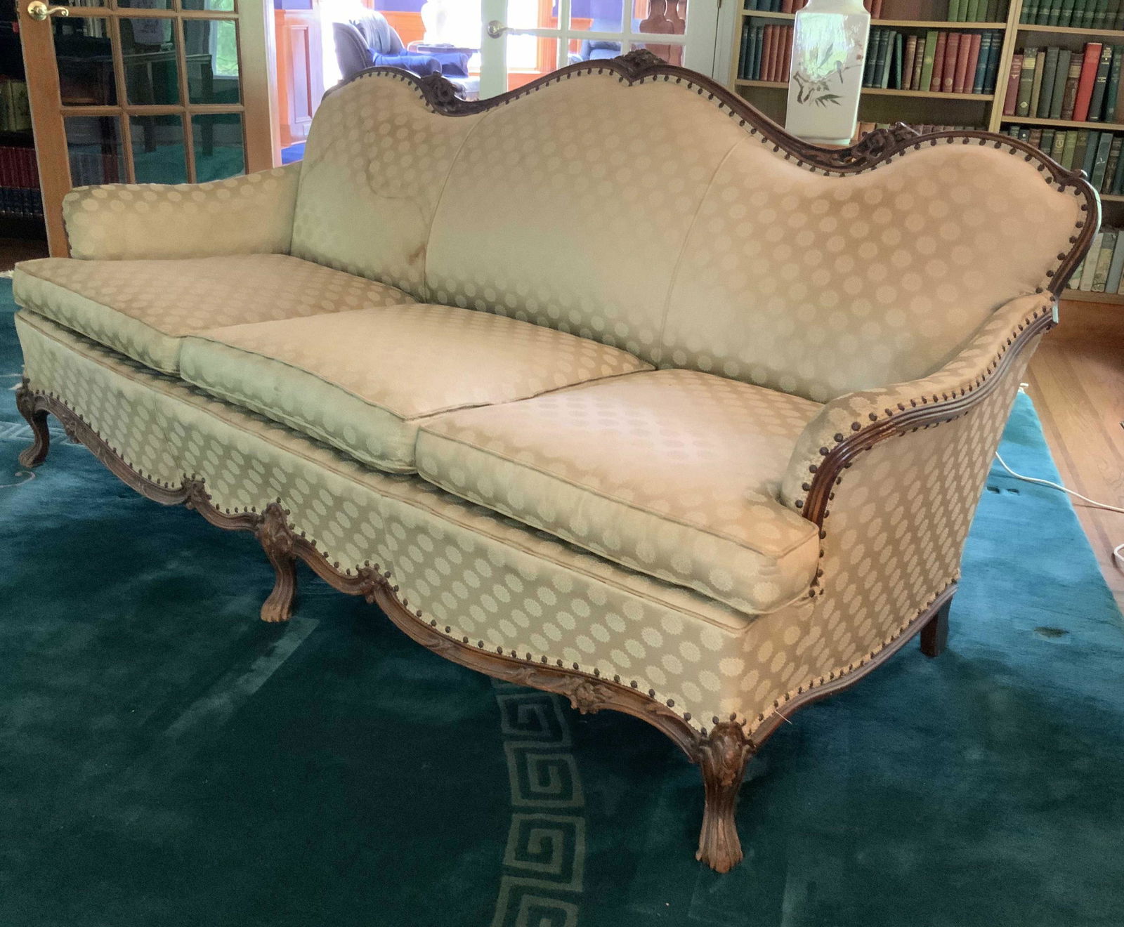 Vintage Carved Wood Framed French Style Sofa: Vintage possibly antique carved wood frame sofa with floral detailing, scalloped apron, scrolled arms and scrolled back, upholstered with tight back and three loose cushion seats, upholstery has stain