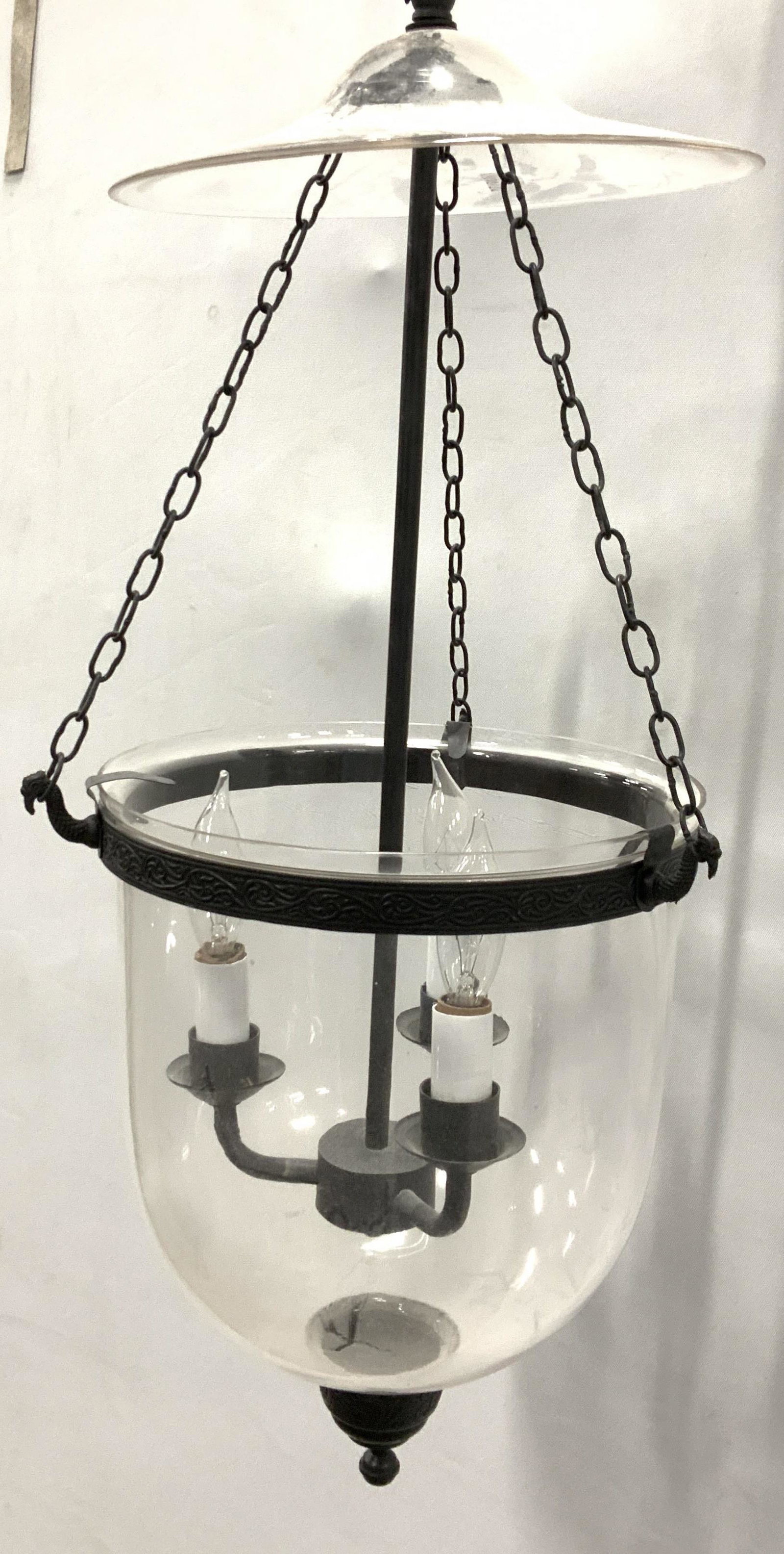 Ceiling Dome Glass Pendant Light: Dark matte metal light accents, drop pendant light connected to chains and glass top plate. 3 chandelier lights inside bowl shape fixture with underside ball point finial. Light itself measures 26.5 i