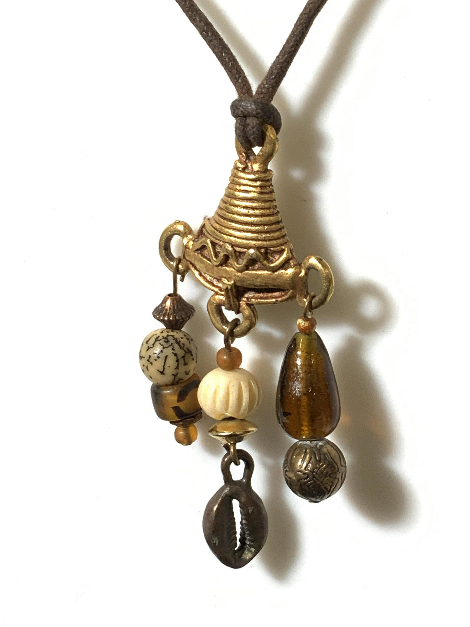 ROBERT ROSE Artisanal Pendant Necklace Jewelry: Artisanal necklace, signed Robert Rose on charm and on version of pendant. Brown rope measures 22 in. Pendant with primitive flair. Some history: ‘American jeweler Robert Rose founded the company in