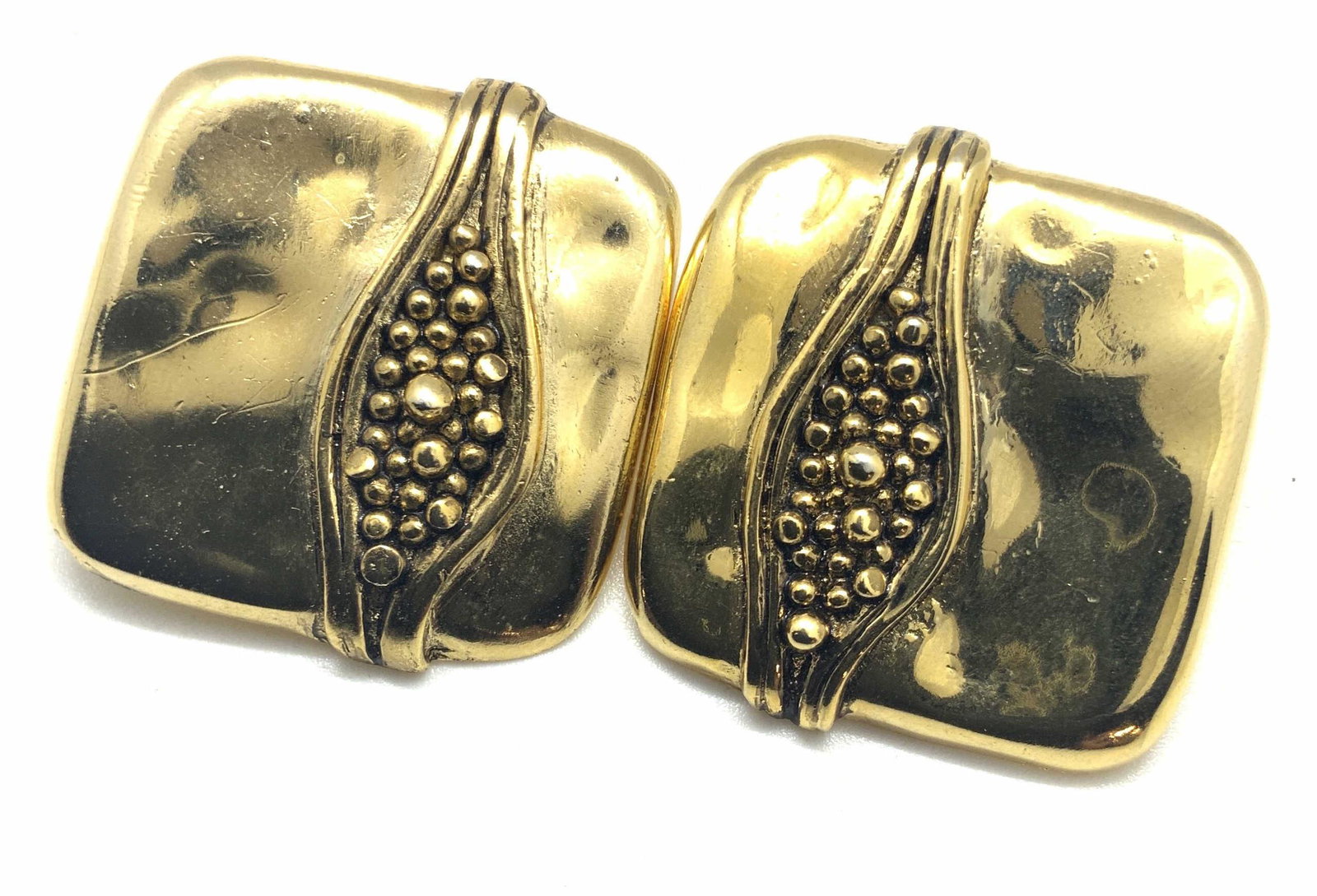 Hammered Gold Tn Square Statement Earrings: Hammered gold tone metal earrings with raised twin lines encasing small, polished metal spheres. The spheres are stacked and raised. Undersides feature clip on backings. Approx. 1.25 x 1.25 in. Statem