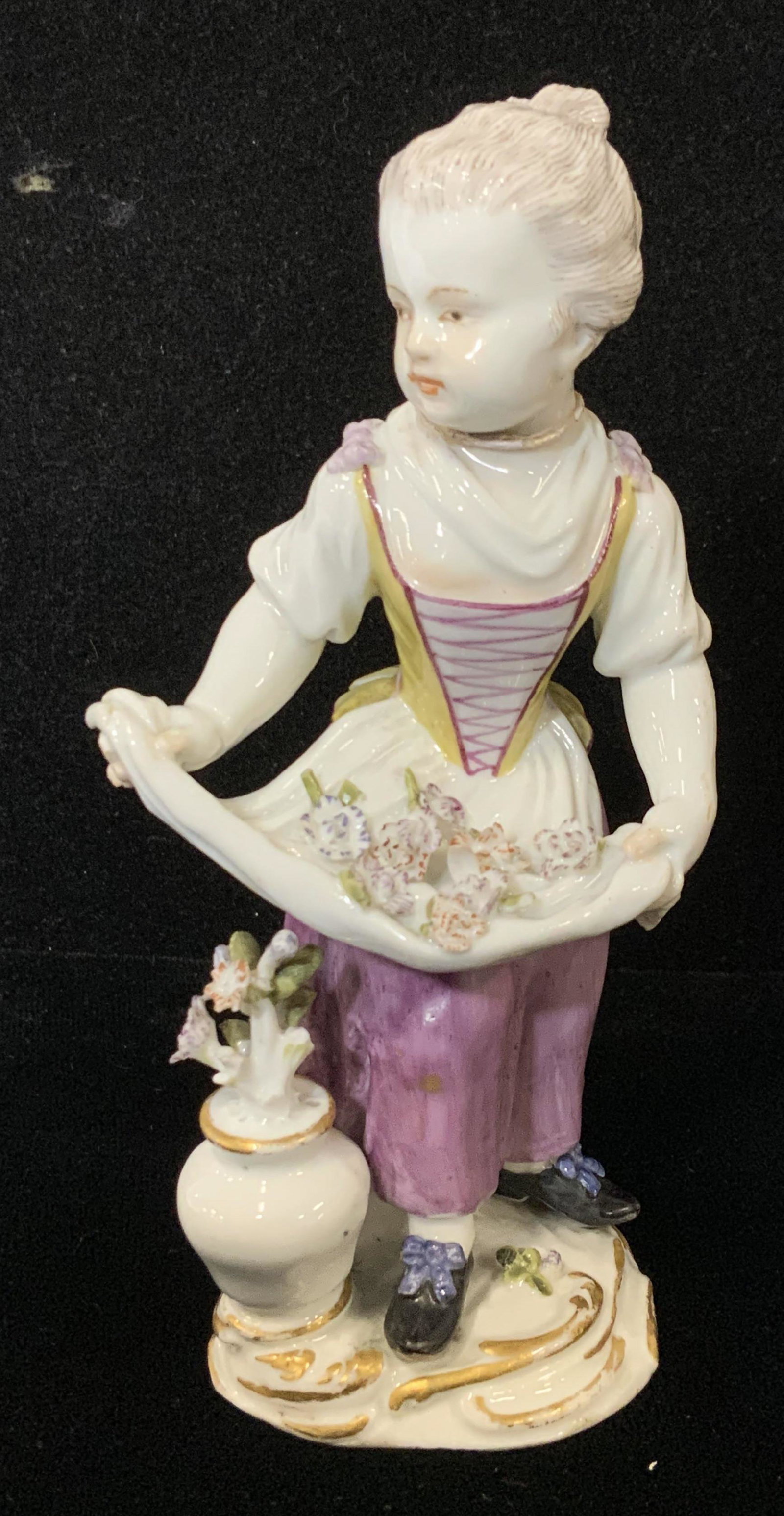 MEISSEN Porcelain Figural, Girl W/Flowers in Apron: Meissen Figural, possibly antique, depicts lady holding flowers in her apron. She has a purple dress, black shoes and a yellow and purple corset. A vase of flowers rests by her side. Hallmarked on bac