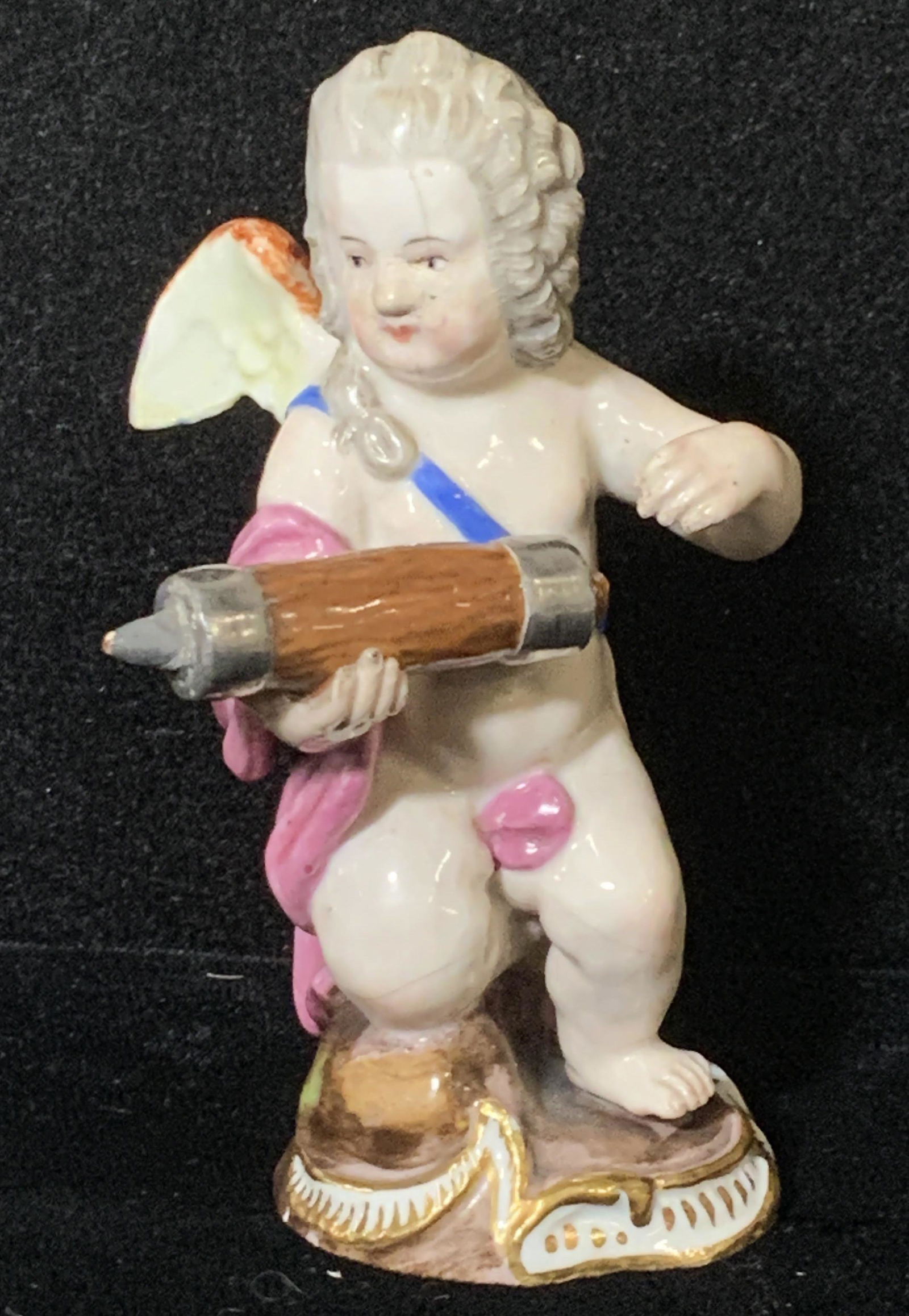 Hallmarked MEISSEN Figural, Male Angel Putti: Hand painted figural of an adult male with grey wig, pink robe and colorful angel wings. Possibly antique. Hallmarked on verso with crossed Meissen swords. Slight glaze crack in face and legs, in very