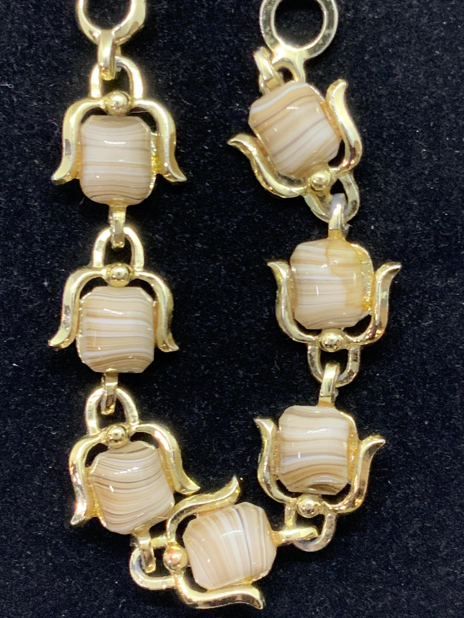 Polished Costume Stone Choker Necklace, Jewelry: A gold tone metal choker necklace with costume stone accents. The stones are polished and various hues of banded brown. Possibly crafted from glass. Piece secures with fishhook clasp closure. Small he