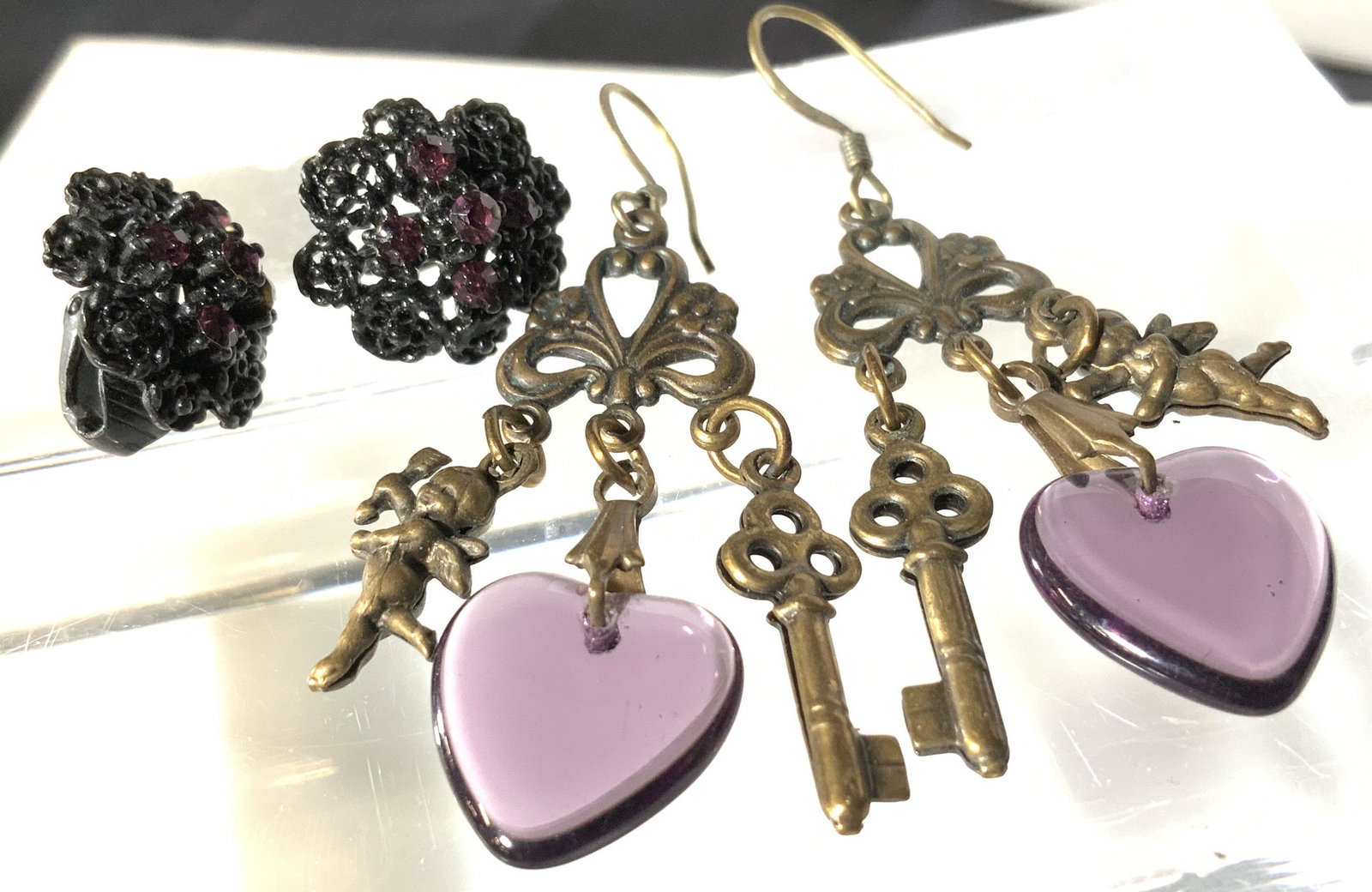 Lot 2 Victorian Style Fashion Earrings, Jewelry: Dangle Fish hook earrings with amethyst color heart charm, Skeleton key charm and Angel charm. Drop is 2 in. Black enamel and purple crystal clip ons, filigree design. Earrings, Victorian Style Earrin