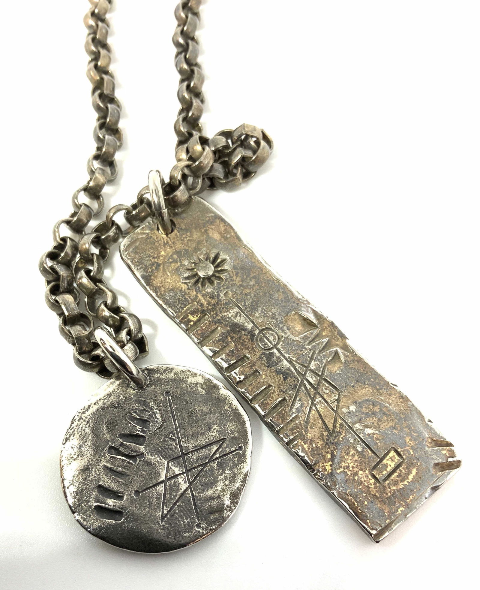 Etched Pendants on Anchor Chain Necklace, Jewelry: 32 in. chain with 2 distinct etched pendants with primitive designs of sun, astral lines, fossils and reads on rectangular bar ‘ MMCMXI’ (yr: 2911) . Other pendant round. Silver toned metal. Unise