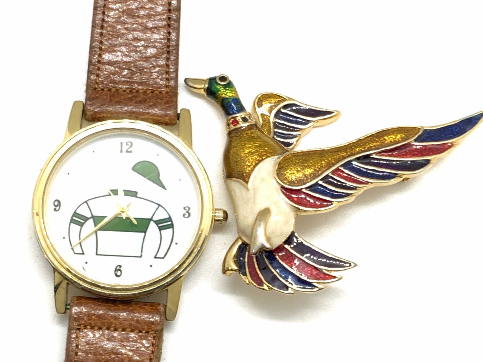 Lot 2 IMAGE Signed Watch & Brooch, Jewelry: The brown toned, leather style watch is gold plated (marked g/p) and features a sweater & hat design on the watch face. The piece is adjustable and secures with a buckle style closure. Underside of wa