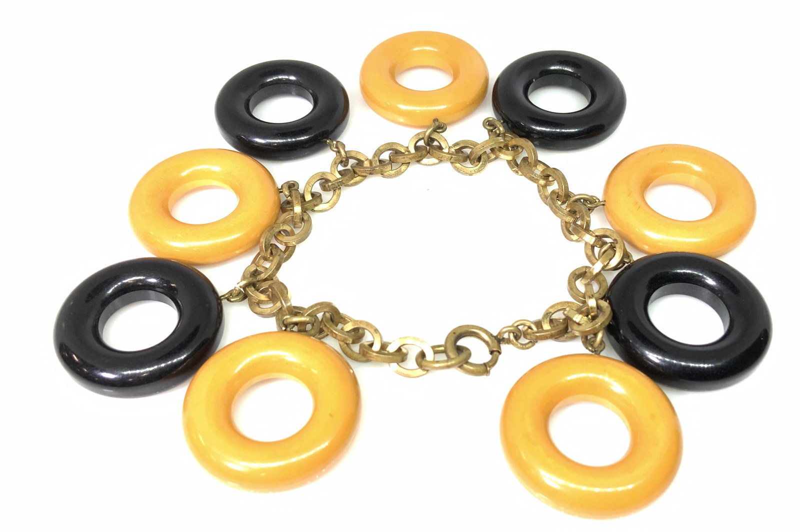 Vintage BAKELITE OPEN CIRCLE Charm Bracelet: Funky and rare to find. Orange and black round Bakelite charms, 4 of each color, Brass toned chain. C spring needs replacing, or if it fits over hand use as is. App 2.25 diameter, charms dangle 1 in. 