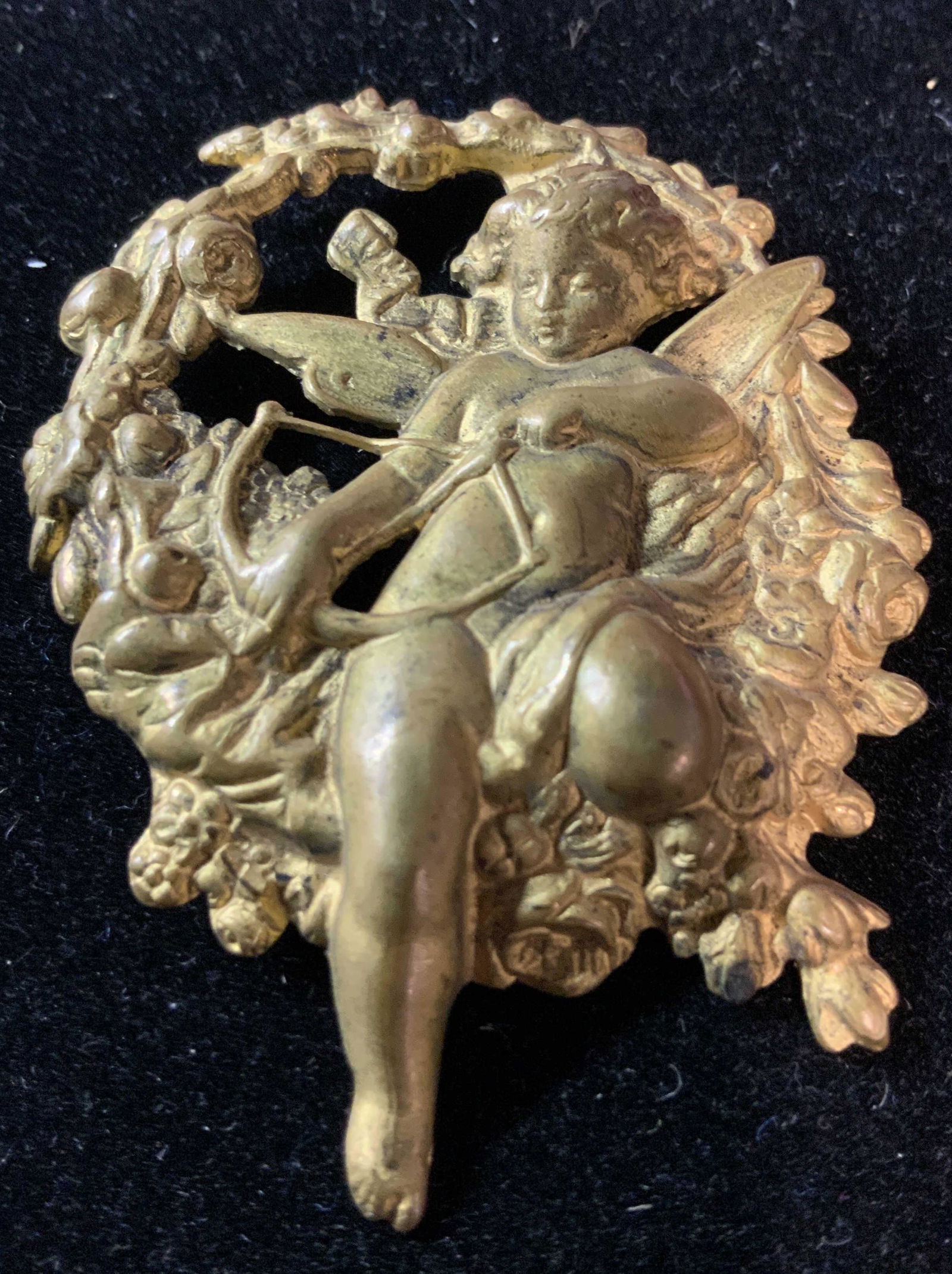 Embossed Metal Angel Putti Accessory/ Pin: Washed Brass coloring, chased and pierced design of Angel sitting on wreathed holding bow and arrow .2 x 1.5 in. Metal Angel Putti Accessory, Putti brooch pin, cherub, Up cycle arts and crafts, costum