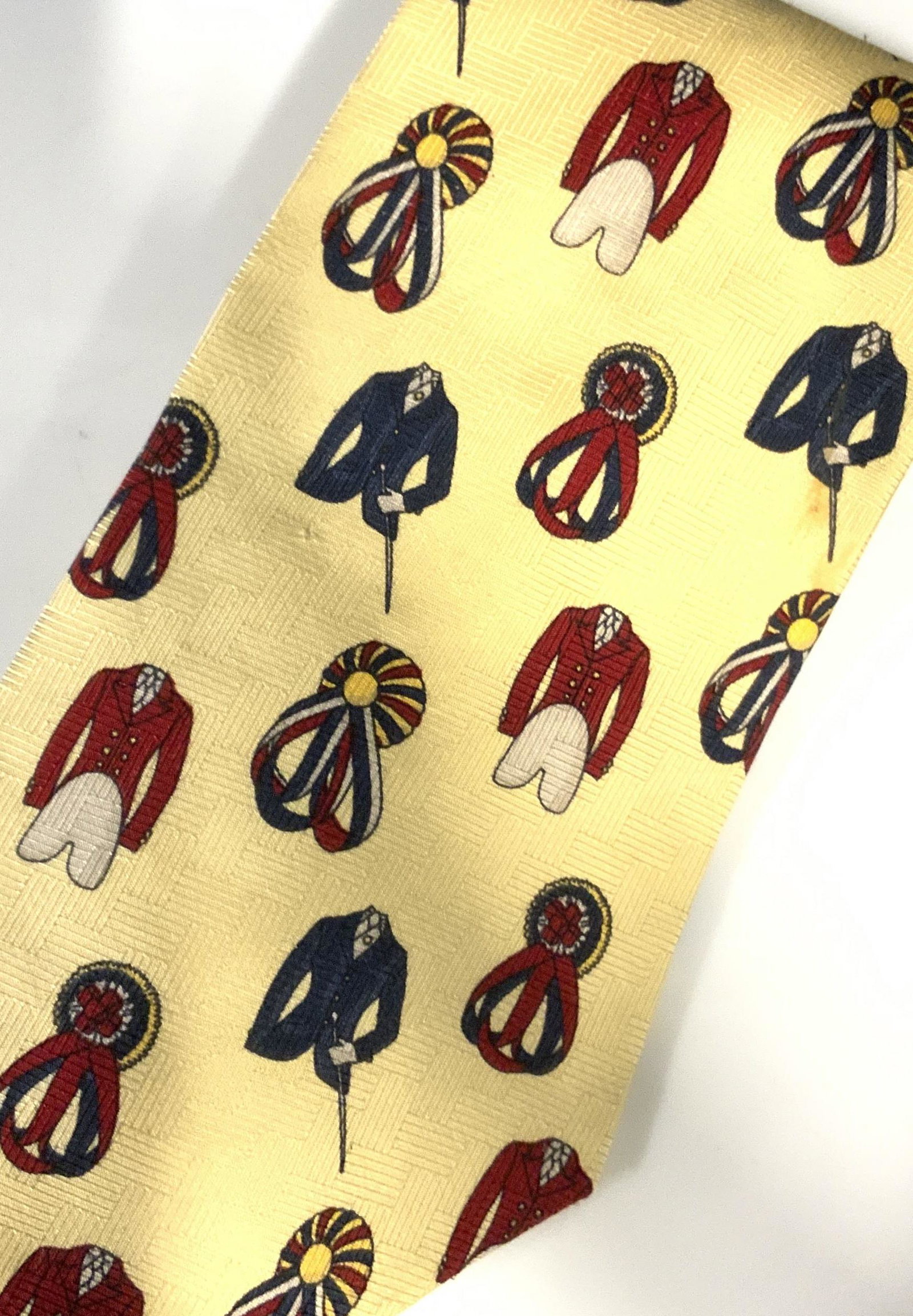 Luxe TOMMY HILFIGER Signed Italian Silk Tie: Silk yellow tie depicts tailored fox hunt coats and ribbon prizes. Front with lion crest royal crown above and laurel wreath. Reads Tommy Hilfiger with trophy. Designer label on verso. Additional labe
