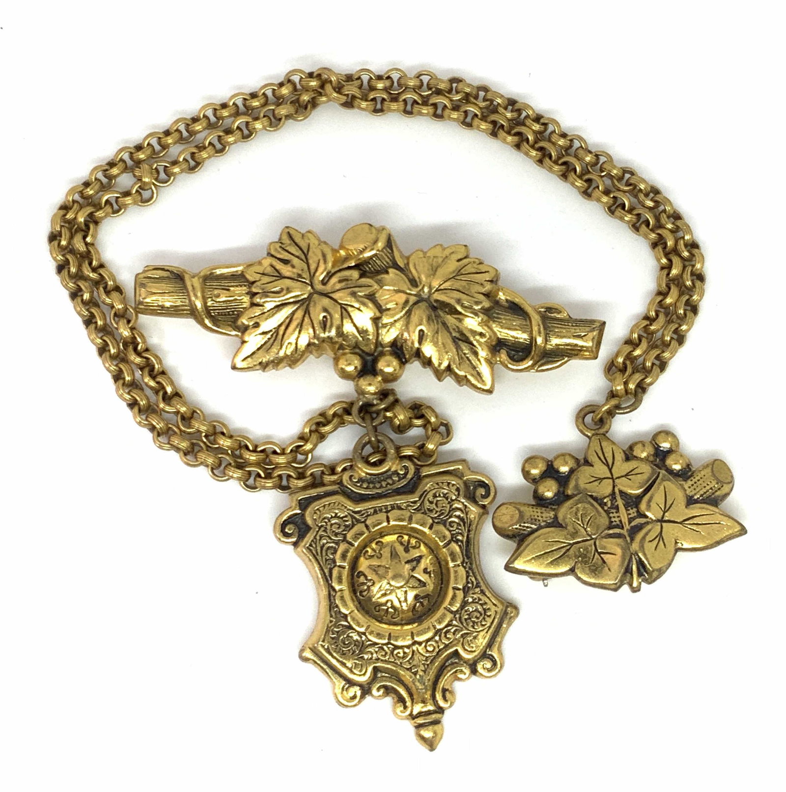 Vintage Nature Motif Metal Sweater Pin: A vintage embossed deep gold tone metal sweater clip. Pins are connected via a dual curb chain. Pins featured embossed & etched metal leaves along branches. One pin has two leaves, the other has three