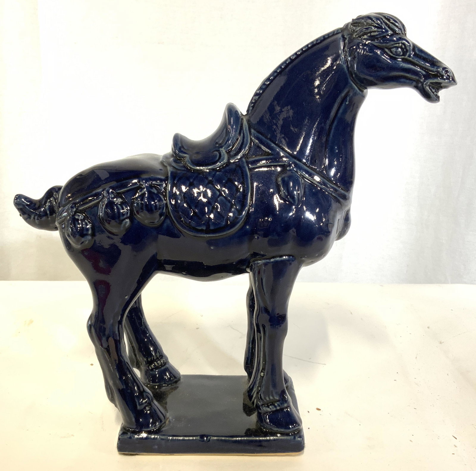 Glazed Ceramic Porcelain Horse Figural: Horse figural appears to be ceramic possibly porcelain. Piece is navy toned and has glazed finish. Figural depicts a standing horse with saddle. Piece measures approx 12 inches tall and deep 4 inches 