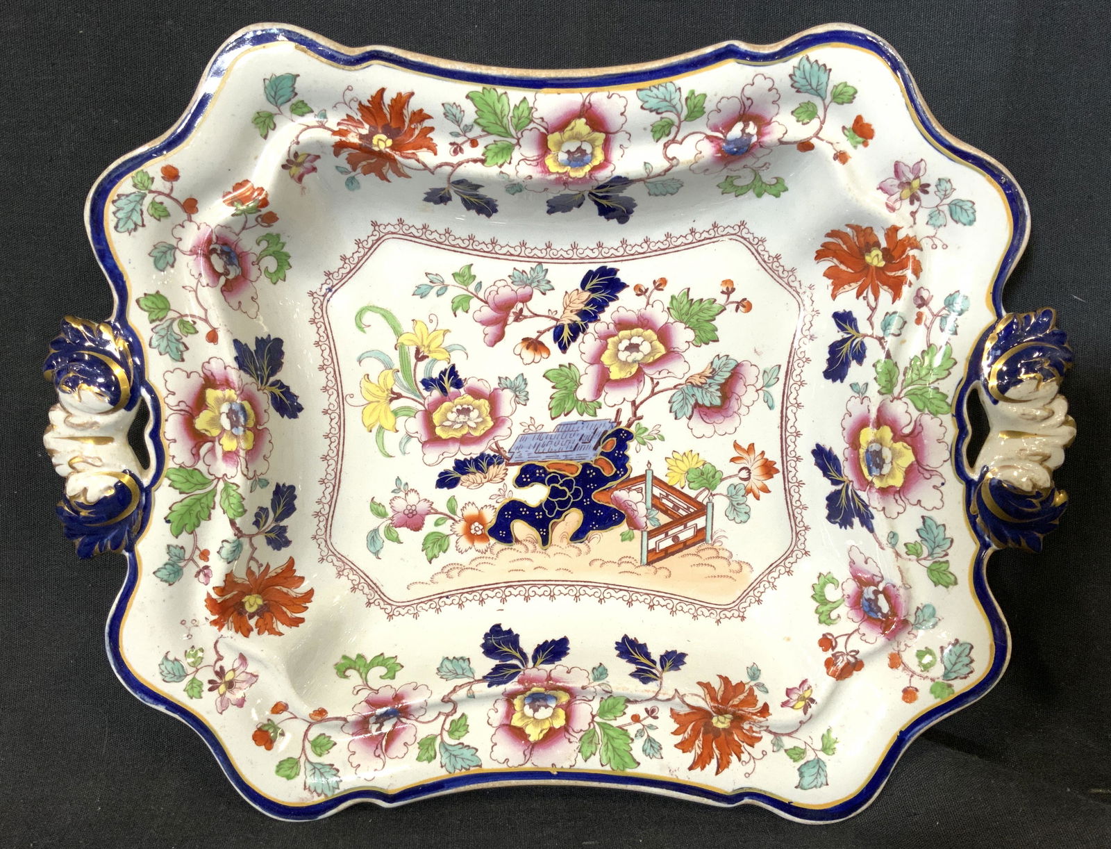 Vintage REAL STONE CHINA Porcelain Serving Dish: Underside of piece is marked REAL STONE CHINA. Serving dish has intricate multi toned floral vine and leaf detail. Serving dish is footed. Piece has handle on each side which appear to have gold leaf