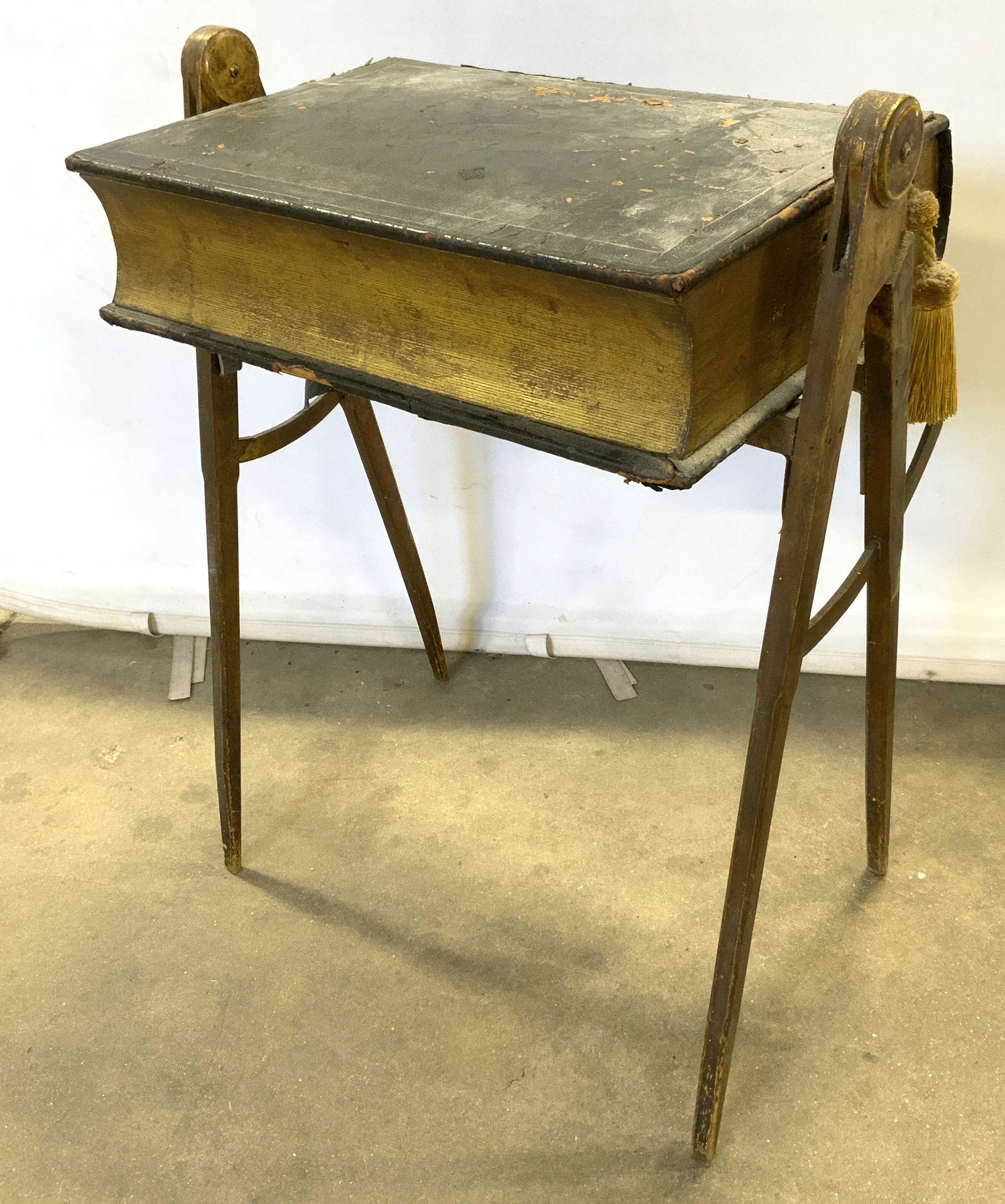 Antique Wood & Leather Side Table: Antique side table. Table top is leather bound, and resembles a book, the book opens to reveal a compartment. A tassel hangs from the book, resembling a book mark. The table legs are carved wood, carv