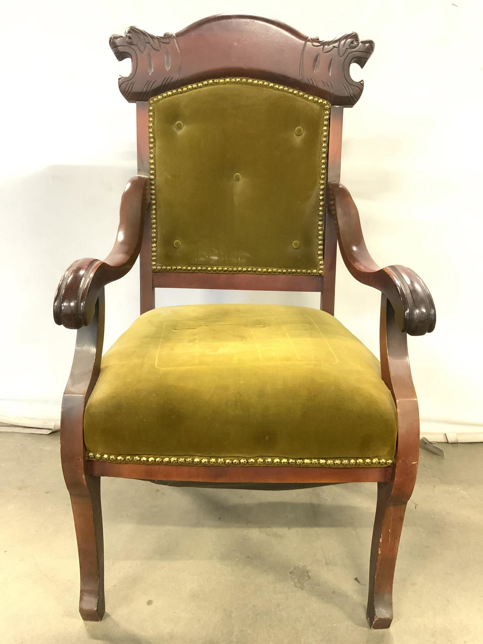 Vntg Wood Upholstered End Chair W Nailhead Detail: Chair is vintage possibly antique. Piece has intricately carved back rests which appears to depict lion or temple lion heads. Chair is upholstered with green toned fabric, possibly crushed velvet. Bac