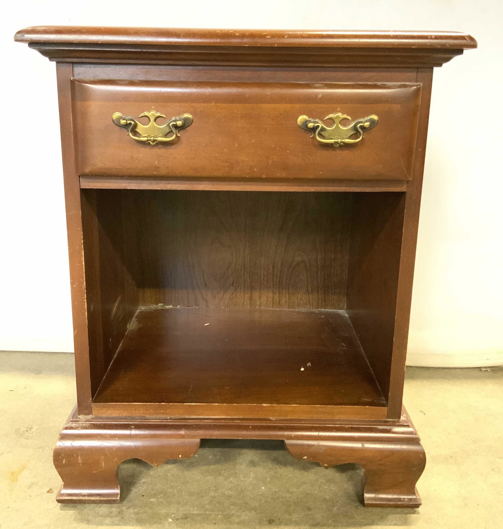 Vintage Carved Wooden Nightstand W Drawer: Nightstand is vintage. Piece has 1 drawer with 2 gold toned dangling handles which appear to be brass. Nightstand also has carved wooden feet. Piece measures approx 25 inches tall 20 inches wide 15 in