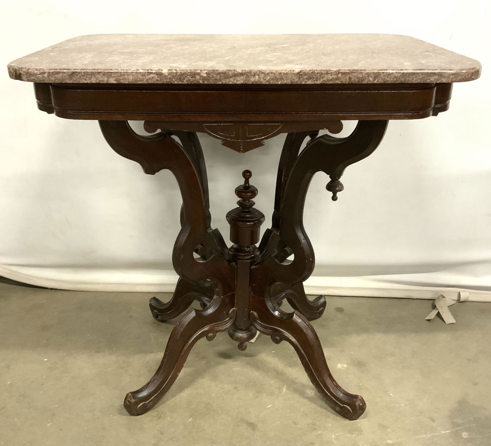 Vintage East Lake Victorian Style Marble Top Table: Vintage, possibly antique, Table has rounded rectangle shaped marble top. Piece has 4 intricately carved wooden legs which meet at center. Piece has Victorian East lake style. Piece measures approx 28
