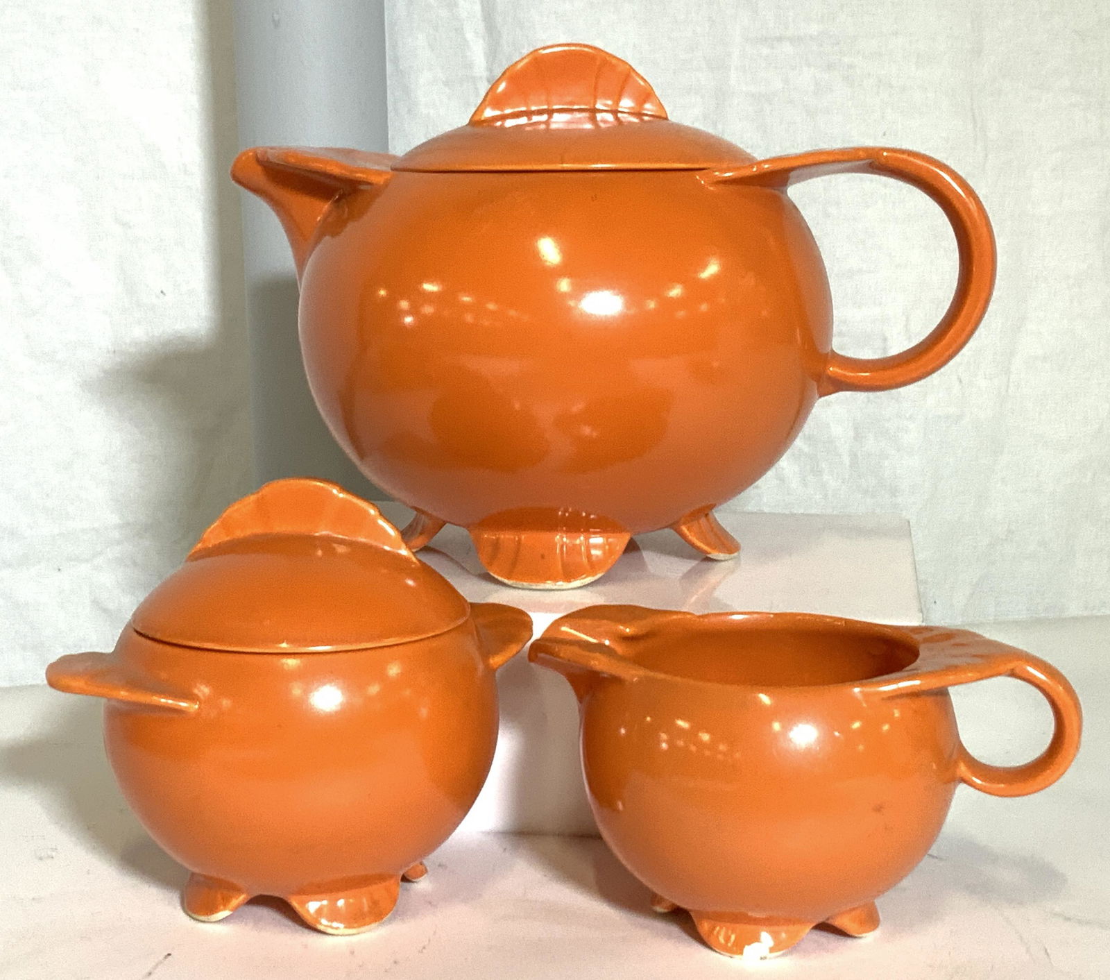 MCM ORANGE PORCELAIN TEA SET 15: Atomic style mid century tea pot set, painted ceramics, consists of tea pot with lid 5 x 9 in. , 2 bowls, creamer, sugar bowl with lid, 10 tea cups ( 3 have rim or paint chip). No marks. Property of M