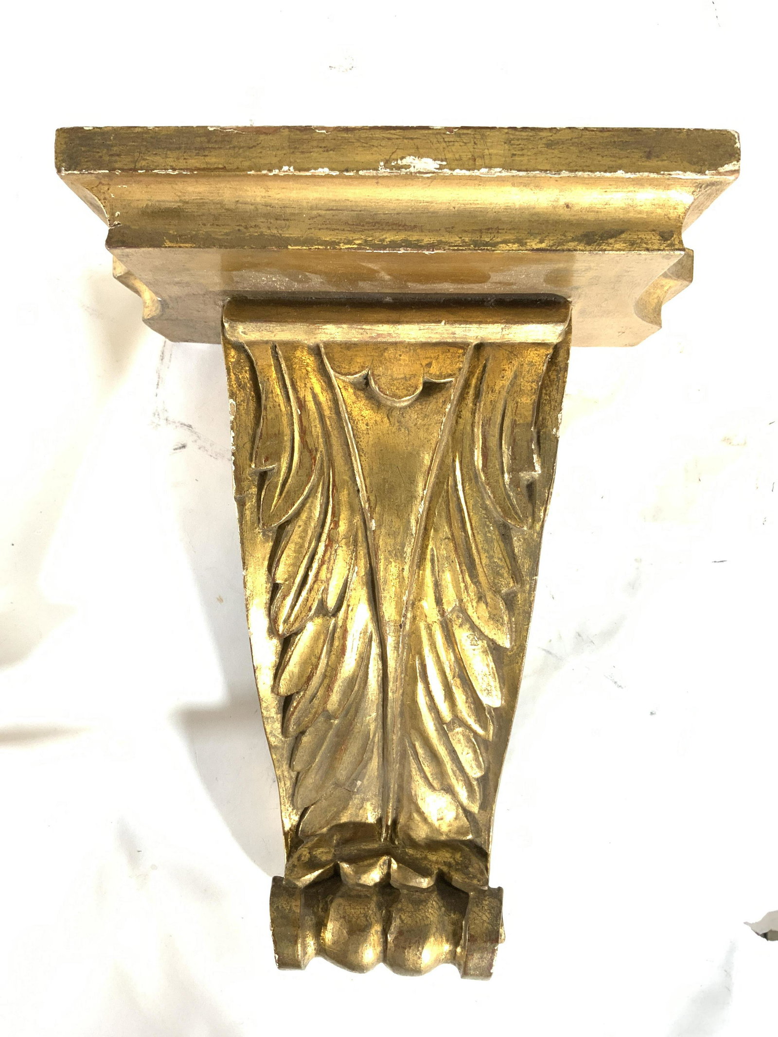 Vintage Wooden Gold Leafed Wall Mount Shelf: Wall mount shelf is vintage. Piece is wooden with gold leafed layer. Shelf support has S scroll shape with leaf detail on front side. Piece measures approx 14 inches tall 11 inches wide 7 inches deep.