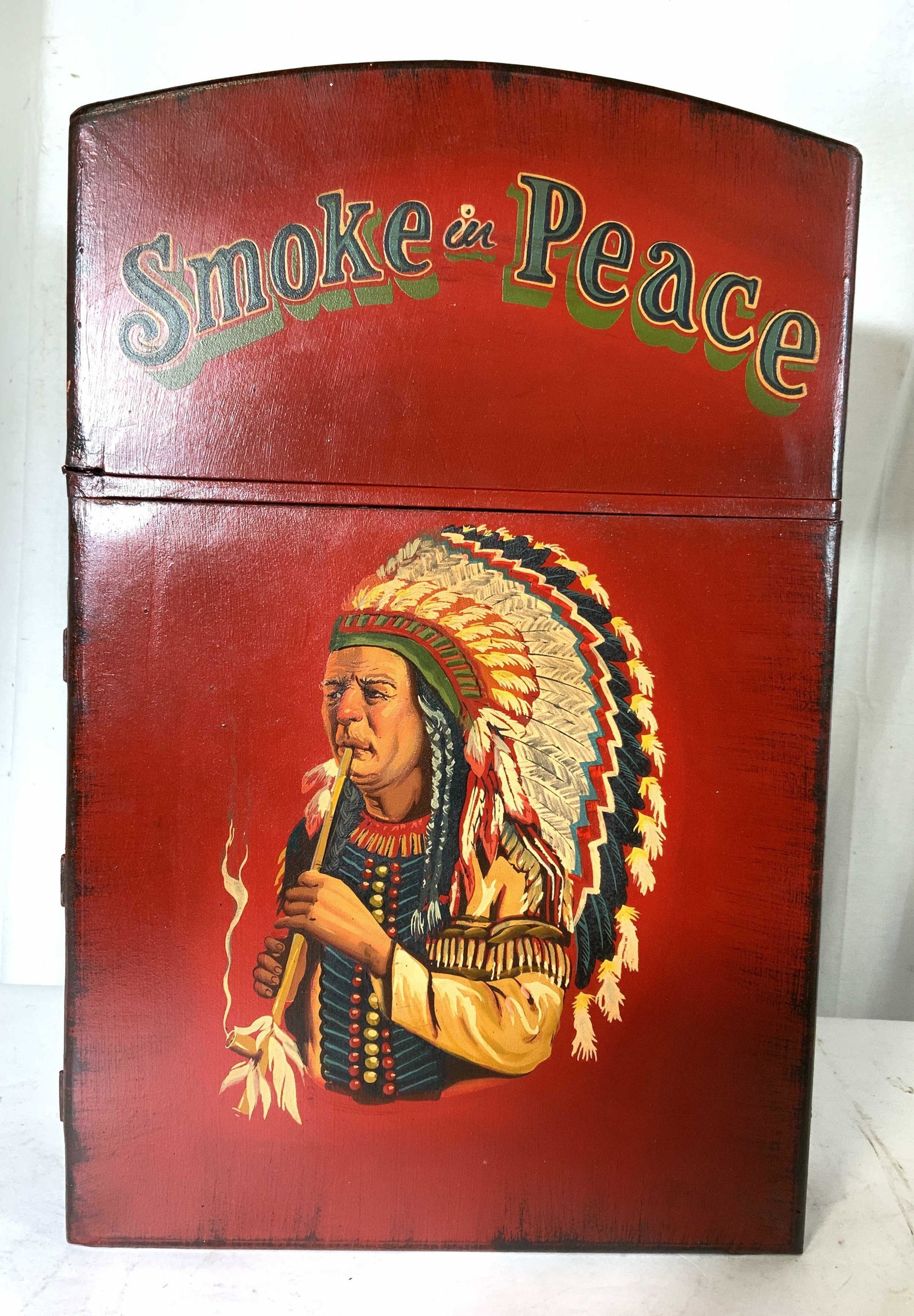 Painted Red Native American Hanging Wall Cabinet: In Shape of Cigarette Lighter top of cabinet reads Smoke in Peace, hinges open in style of classic cigarette lighter, top shelf has the wood mechanism of lighter and center brush where flame would nor
