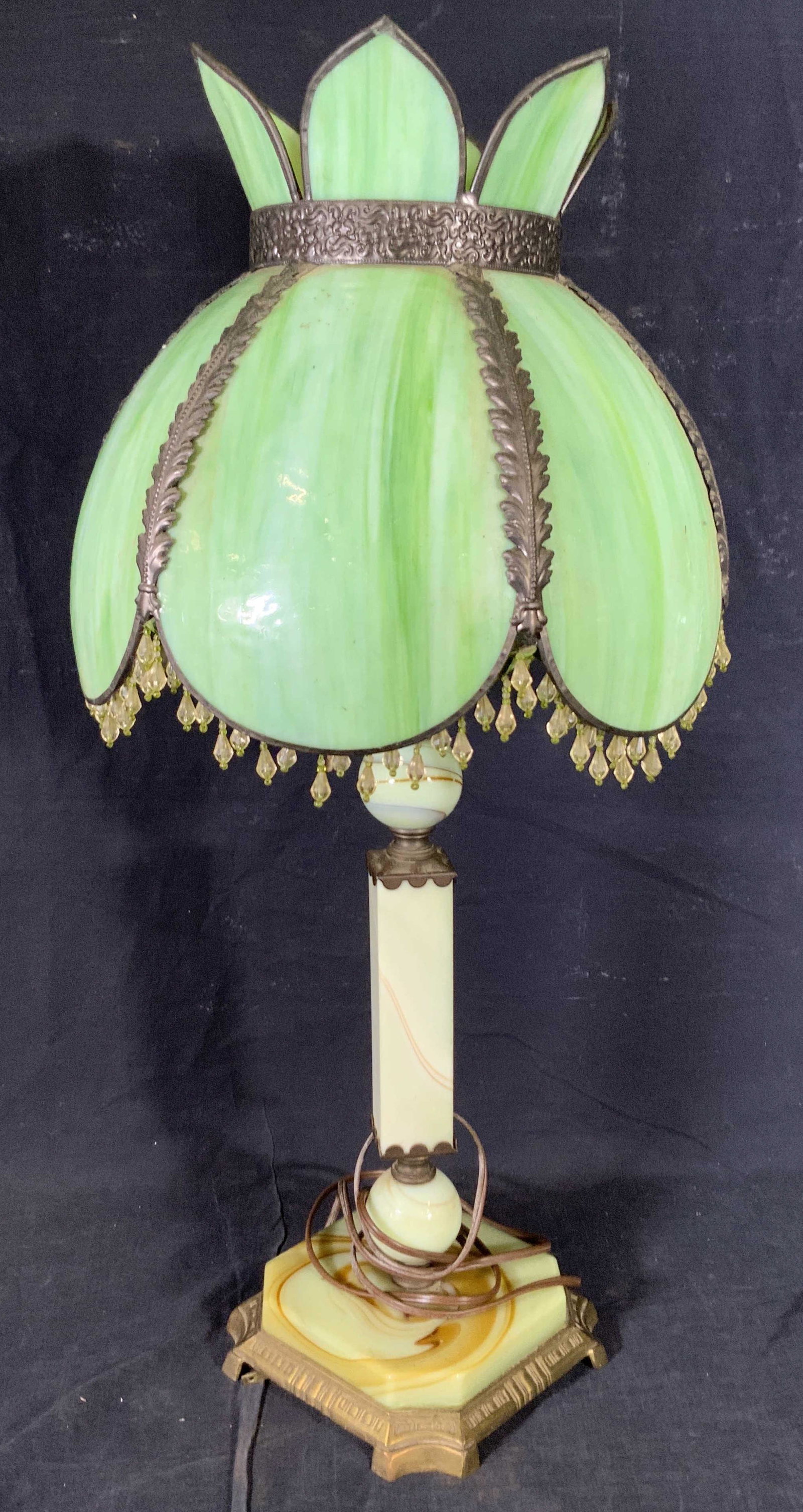 Vintage Green Art Glass Tabletop Lamp: A vintage, possibly antique, art glass lamp. The base and lampshade are both crafted from glass. Dangling, faceted beads adorn the rim of the lampshade. The piece features silver tone metal accents al