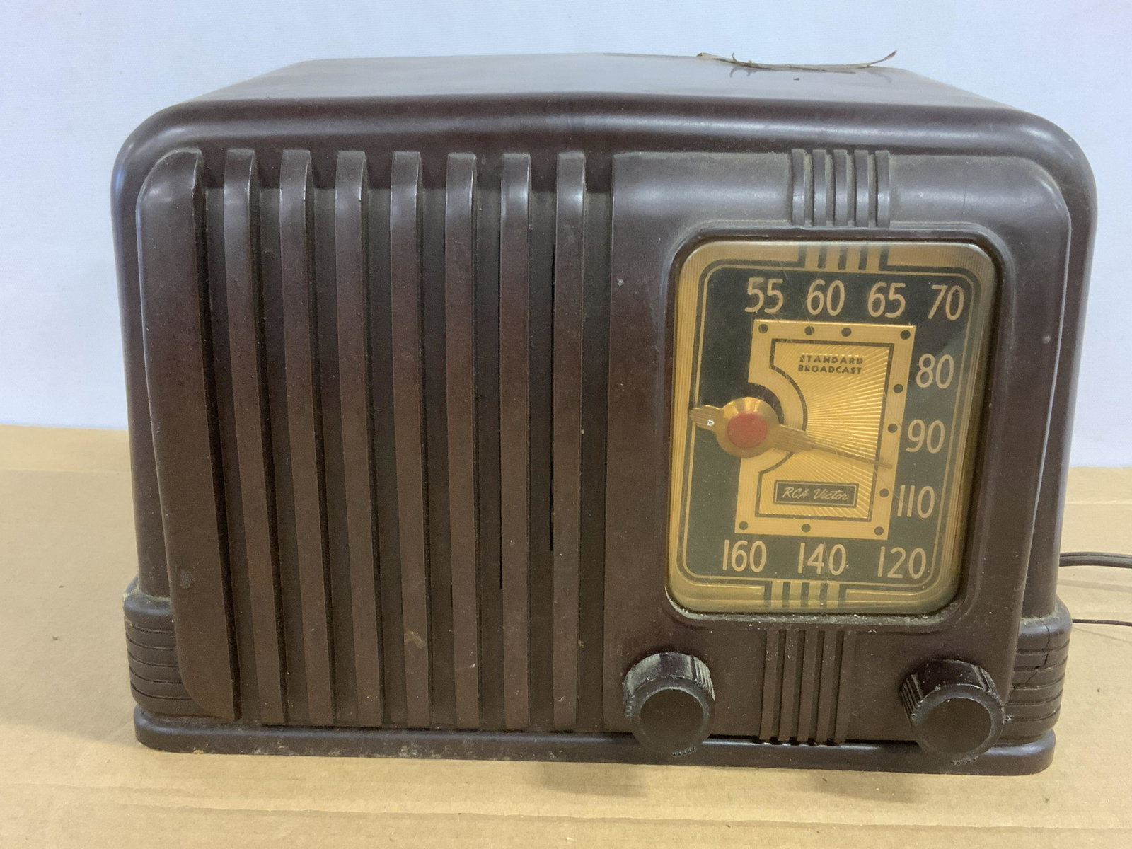 Vintage RCA VICTOR Collectible Radio: Art Deco design, Made of brown BAKELITE, volume dial and channel dial. Art Deco dial hand. Significant wear present, cracking to case. Measures approx 6.5 inches H, and 10 inches W. Part of a larger c