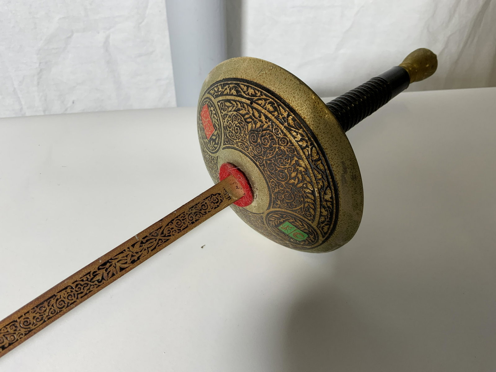 Pair Decorative Fencing Foils: Pair Decorative Fencing Foils, coat of arms shield the the guard in green displaying a crescent moon and lion, guard and base of blade display vine designs in black and gold, grip of foil decorated as