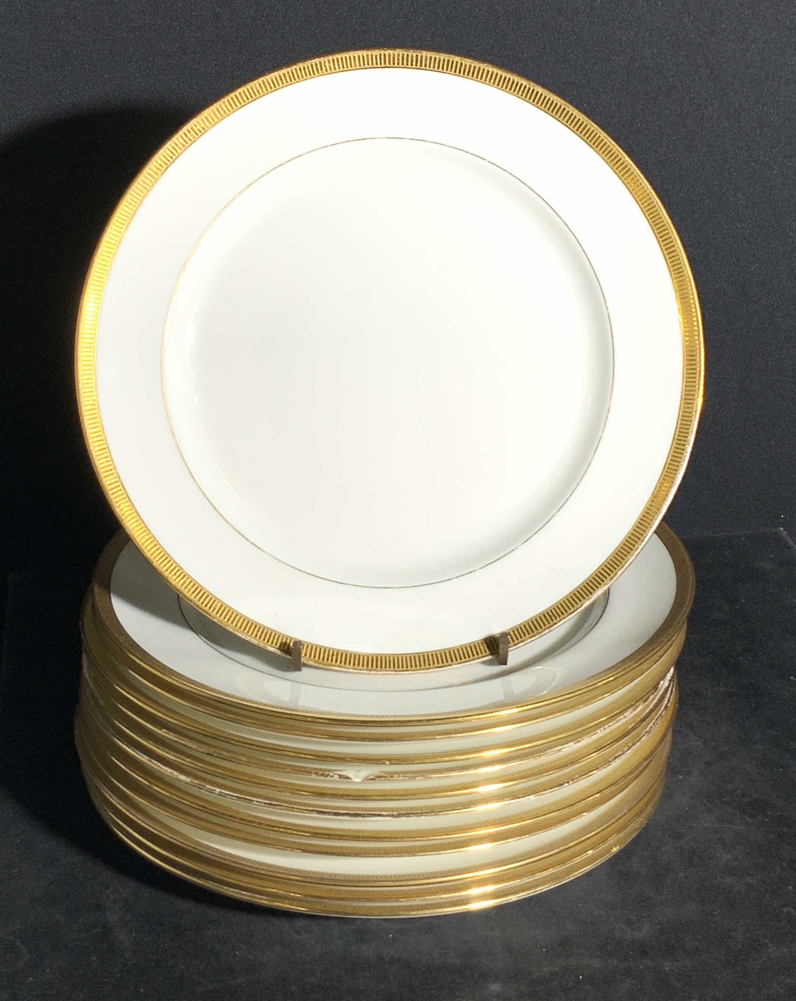 Set 12 LENOX TIFFANY & CO. Signed Porcelain Plates: Twelve white porcelain plates with gilt accents. The gilt border around the rim is slightly raised. The underside is stamped LENOX, TIFFANY & CO. Approx, 8 x 8 in. Some wear to pieces consistent with 