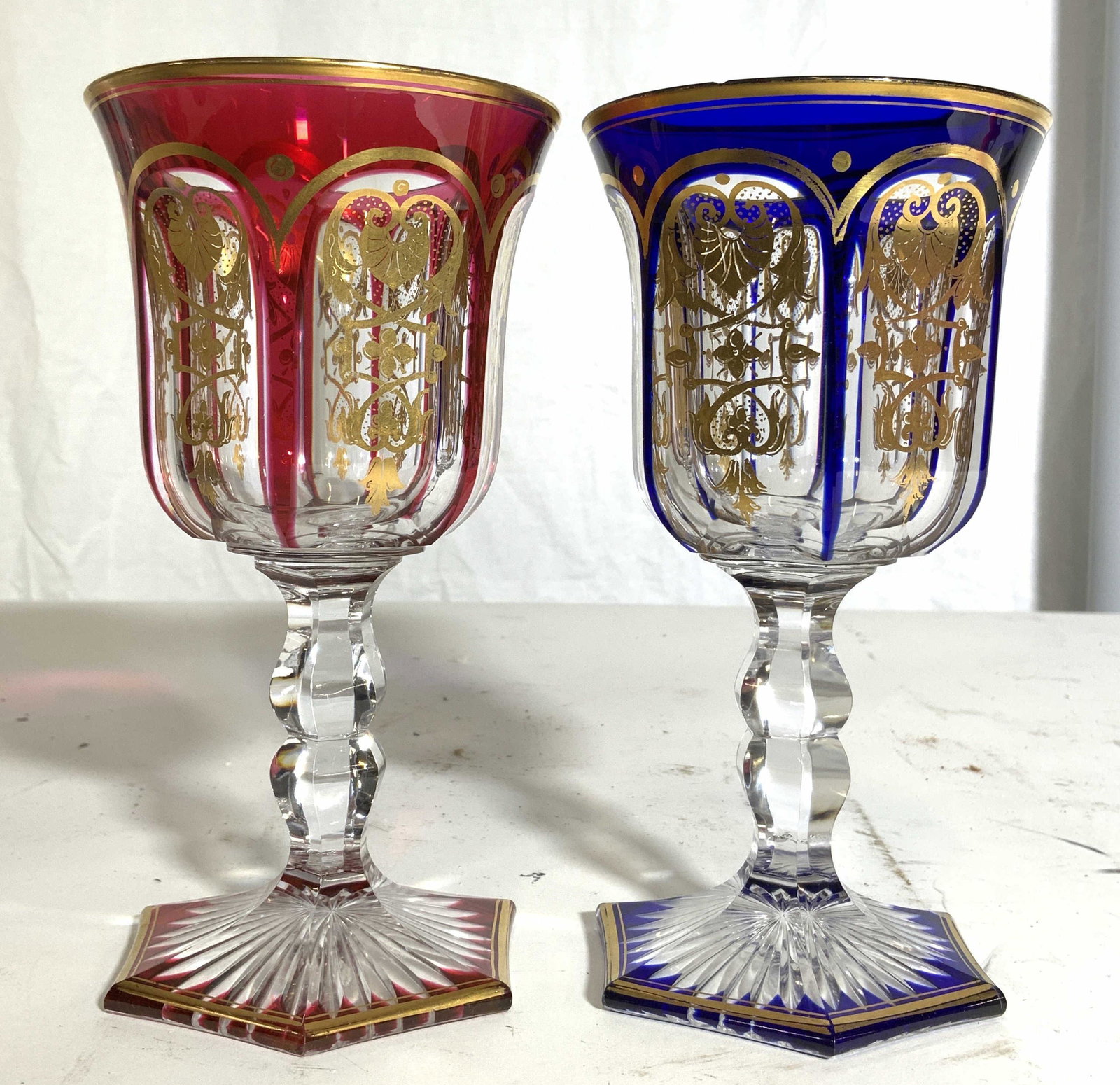 Lot 2 Bohemian Glass Stemware Goblets: Lot includes 2 goblets. One cranberry the other royal blue toned. Each has intricate ornate gold toned detail. Goblets appear to be Crystal. Goblets, chalices, stemware, bohemian glass, Art glass, Cry