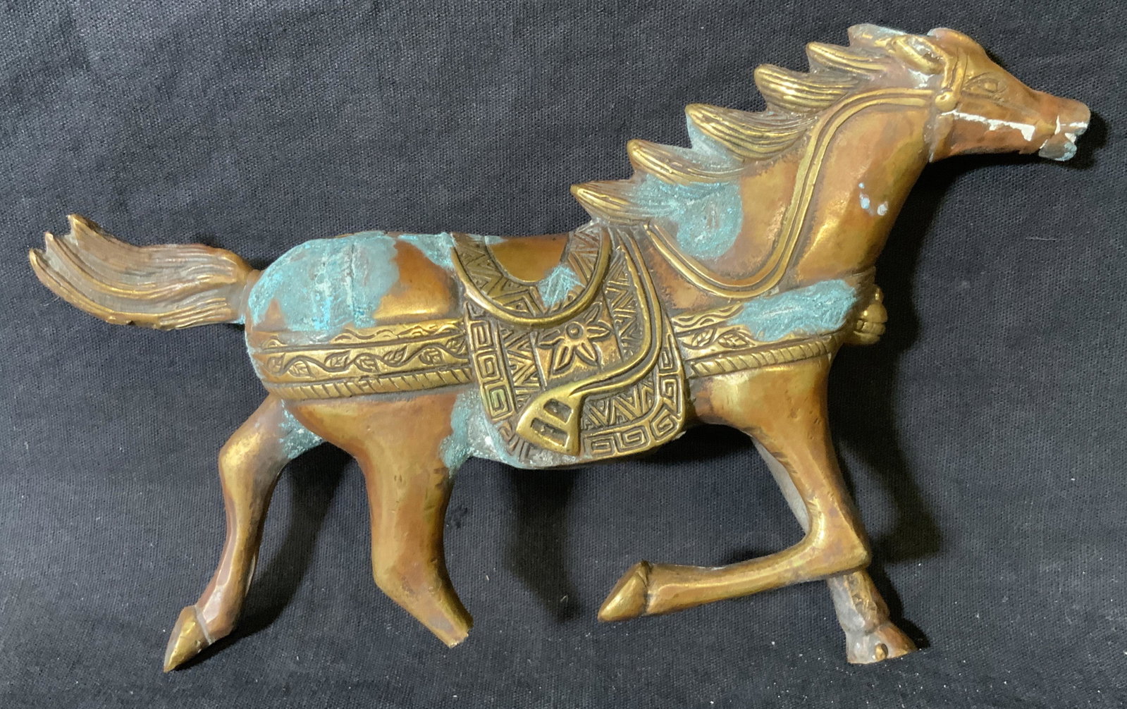 Metal Horse Statue, Decorative Arts: Metal horse statue, no apparent inscriptions or markings, subject a horse mid stride with ornate saddle, back right leg of dragon has broken off some oxidation to piece possibly bronze, piece measures