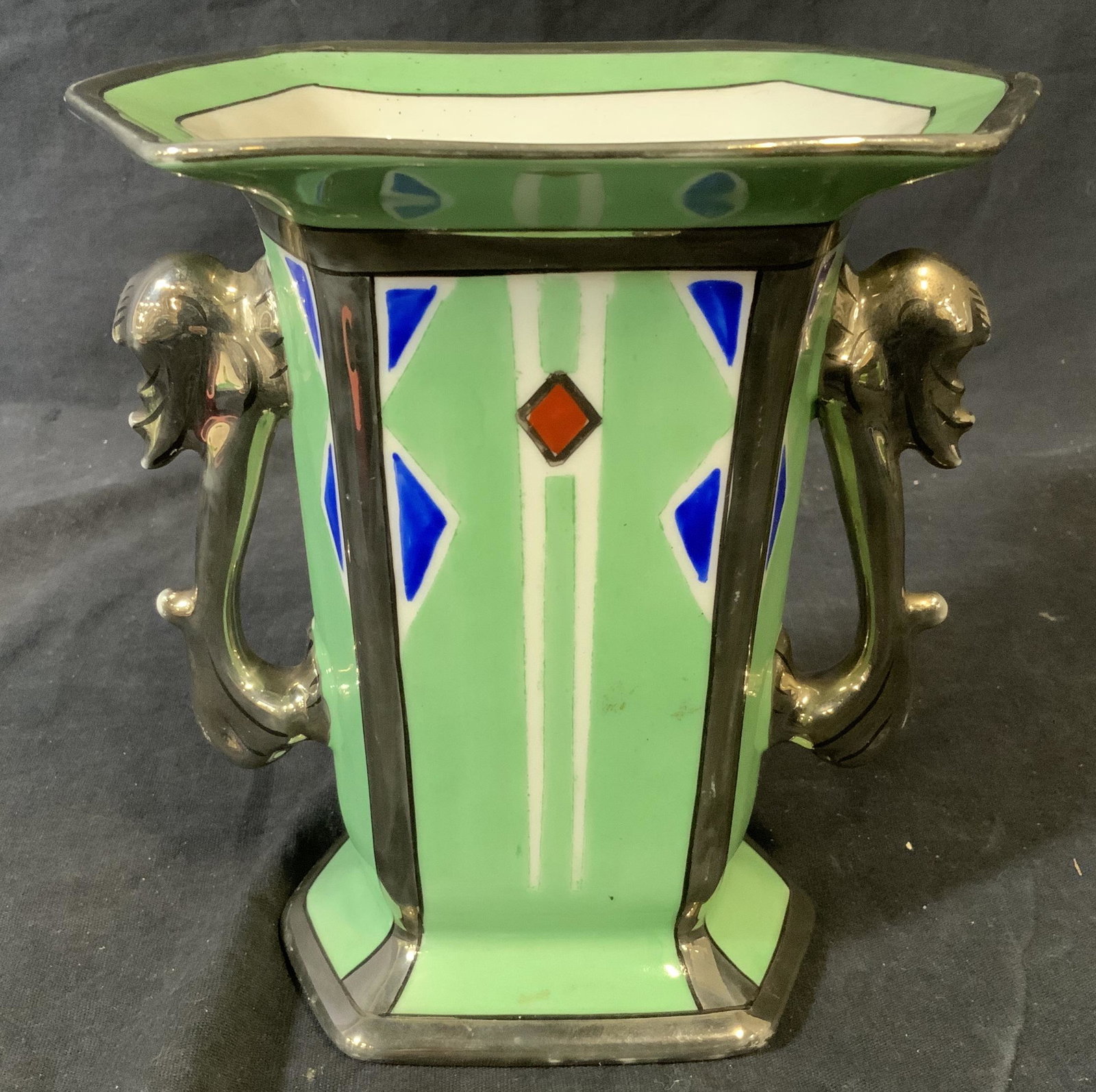 Noritake Japanese Porcelain Vase: Noritake Japanese Porcelain Vase, stamp to underside of vase reads ‘Noritake Handpainted, Made in Japan’, vase itself painted green and silver with blue and orange accents, has a handle to each si