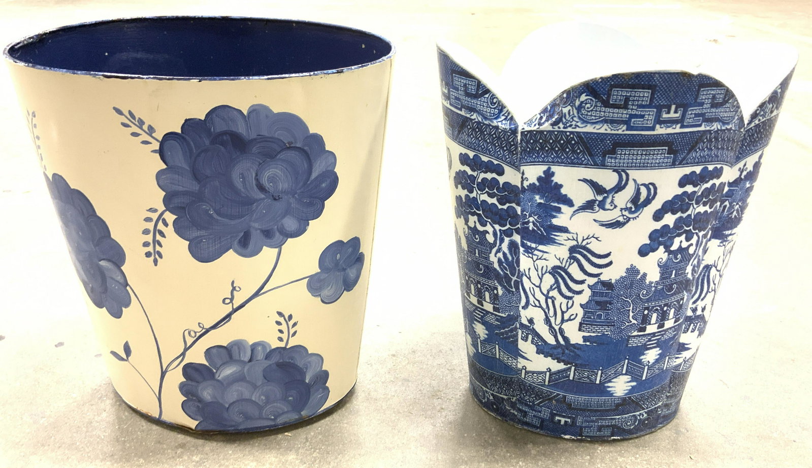 Lot 2 Blue & White Metal Vessels: Two blue and white metal bins. One appears to be hand painted, decorated with art depicting flowers. The there is wrapped in a print and finished with what appears to be lacquer, the under side is lab