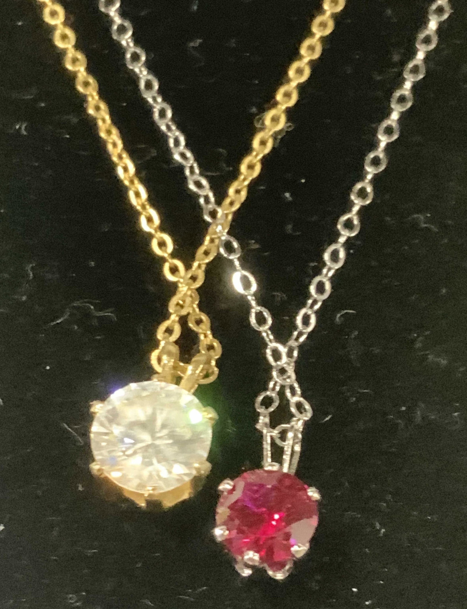 Lot 2 Solitaire Pendant Necklaces, Simulated Ruby: Gold tone chain 16 in. with 8 mm solitaire clear crystal in prong setting. Near clasp reads NS. Sterling Silver chain 16 in. with 6 mm simulated ruby ( tests positive for ruby on gem tester) in prong 