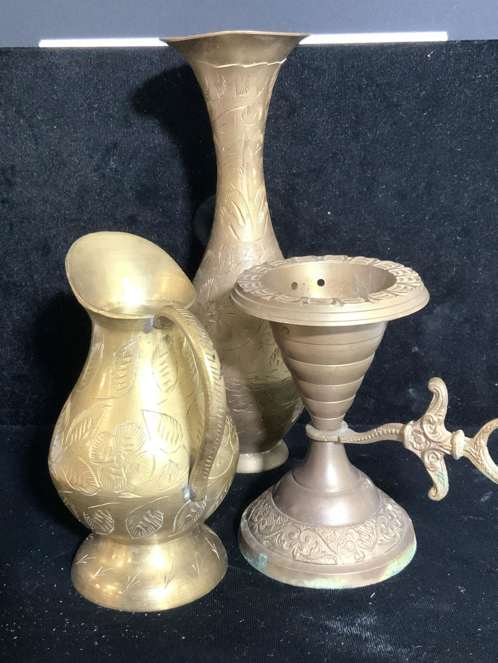 Group 3 Etched Brass Tabletop Accessories: Embossed or etched brass ware. Tall chamber stick candle holder with makers hammered Mark ‘India’ 4.5 in. Tall 5 in. W. Fissure to metal. Flower vase also with makers Mark ‘ India’, 7 3/4 in.
