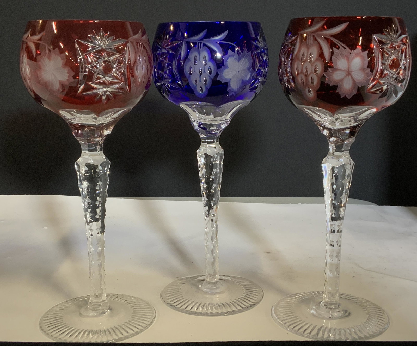 Set 3 Cranberry and Cobalt crystal Bohemia Glasses: Colored Crystal tall goblets, cut crystal with grape bunch and grape leaf decor. App 8.25 in. Ht. Goblet width 3.5 in. Luxury bar ware, Bohemia Crystalware, Pedestal Crystal glasses, cranberry red, co