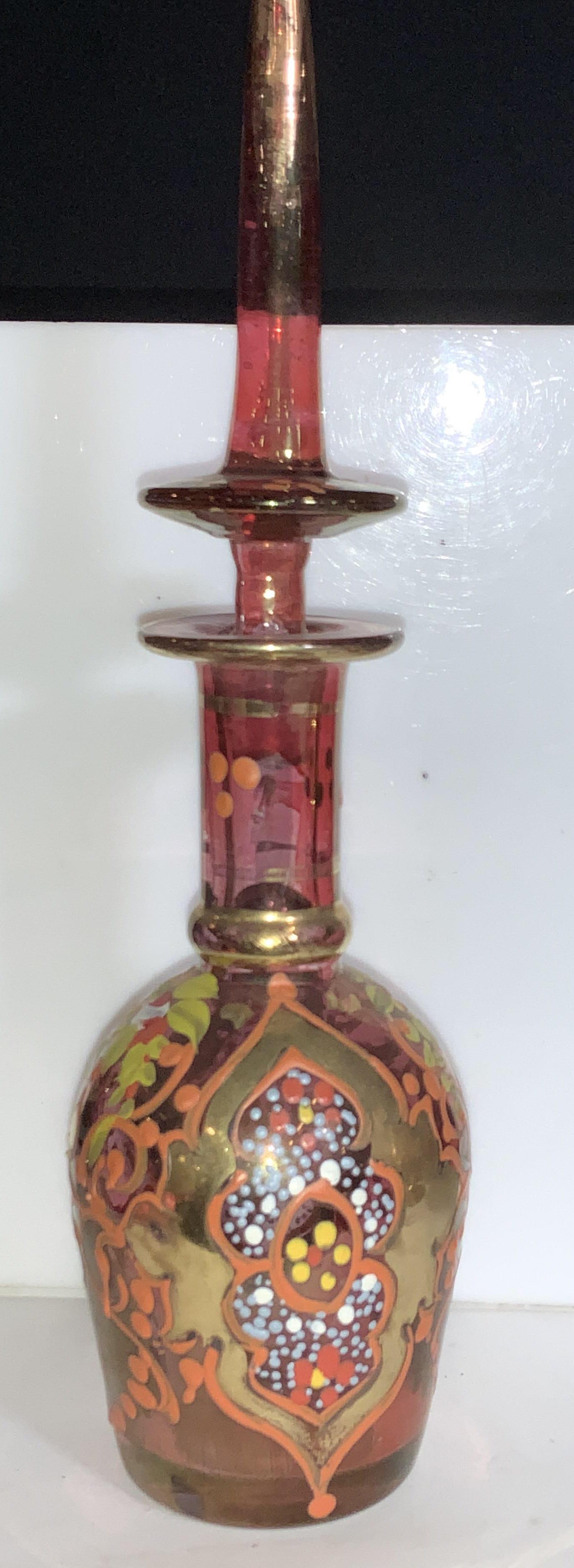 Handmade Middle Eastern Motif Art Glass Bottle: Lovely hand painted Bohemia style perfume bottle, decor bottle. Gilded on stopper tip and pattern on glass. Handmade art glass with iridescent light cranberry coating. Pattern resembles designs native