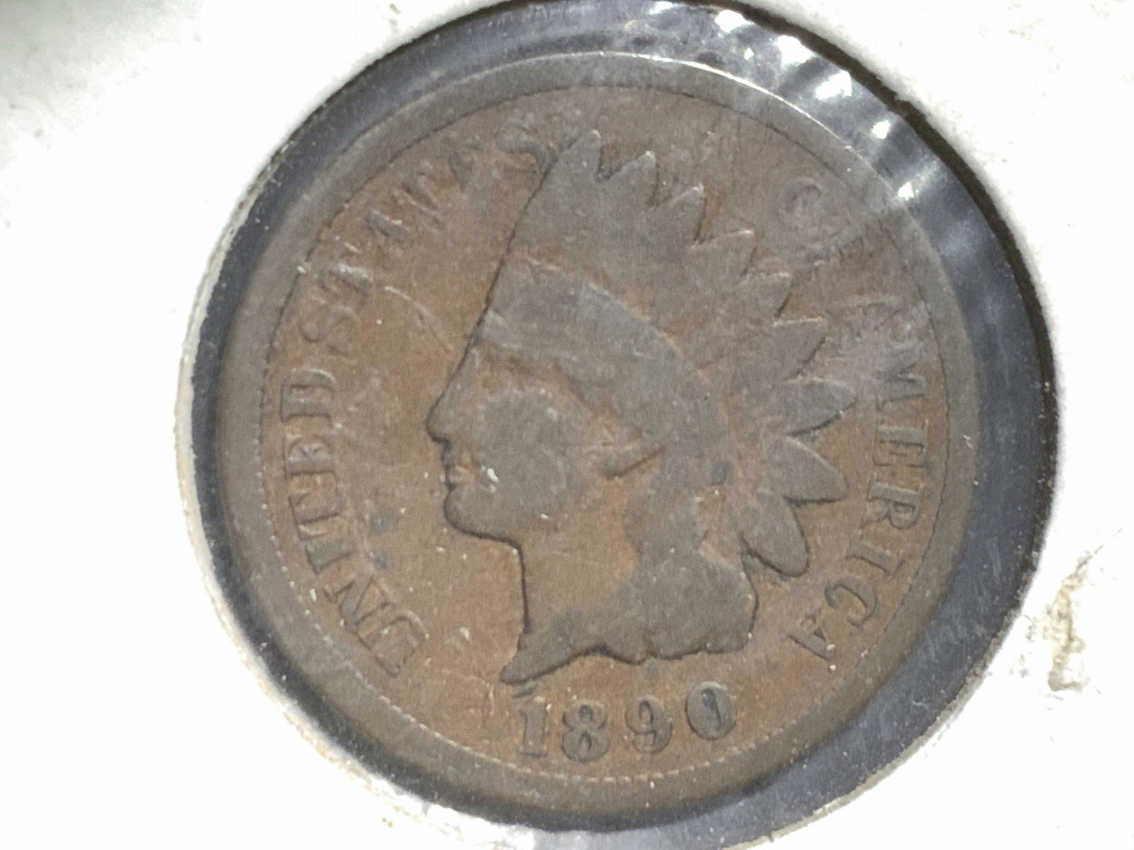 Antq Collectible Currency, 1890 Indian Head Penny: A collectible 1890 antique Indian Head penny. Penny obverse depicts a Native American wearing a headdress. Text reads: UNITED STATES OF AMERICA, 1890. Reverse reads: ONE CENT. Penny is sealed in a cas