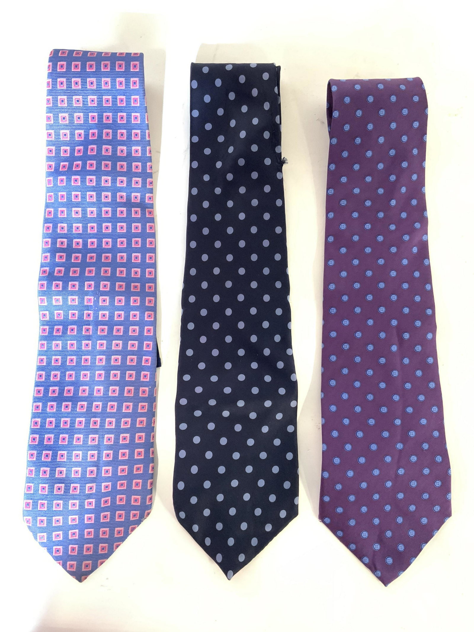 Group Lot 3 Men’s Silk Neckties: Lot includes 3 Neckties. 1 CHERESKIN with button pattern detail , 1 Geoffrey Beene with polka dot detail & 1 GRANT THOMAS with Geometric square pattern detail pattern detail. Each measures approx 55 i