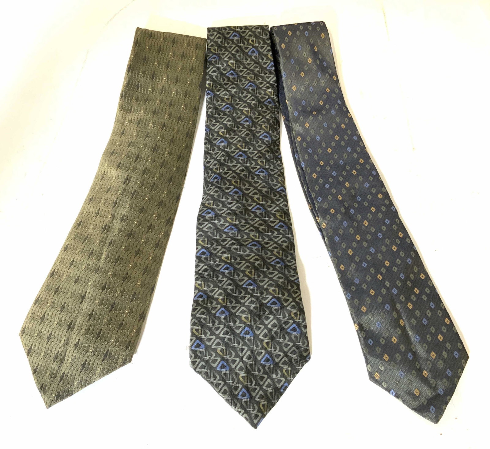 Group Lot 3 Men’s Silk & Polyester Neckties: Lot includes 3 Neckties. 1 WILKE RODRIGUEZ with multi toned diamond shaped detail, 1 VAN HUESEN triangle pattern detail, & 1 STANLEY BLACKER with Diamond pattern detail. Each measures approx 55 inches