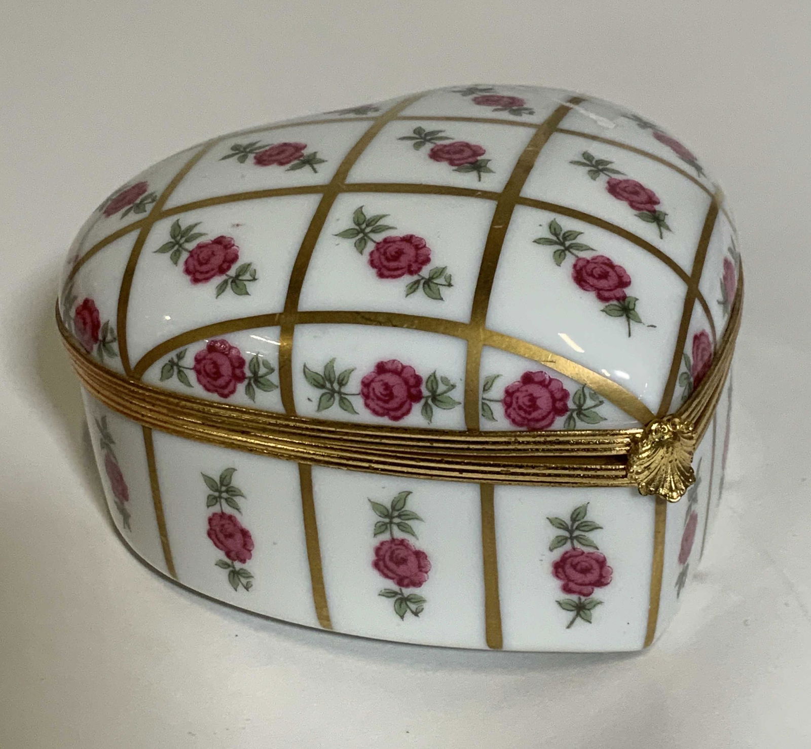 LIMOGES FRANCE PORCELAIN HEART BOX: Porcelain heart shape trinket box with hand painted roses and gilt. Hallmarked Limoges France on verso. Hinged lid, needs adjustment to snap fully closed. 4 in. W, 1.75 in ht. Limoges France trinket b