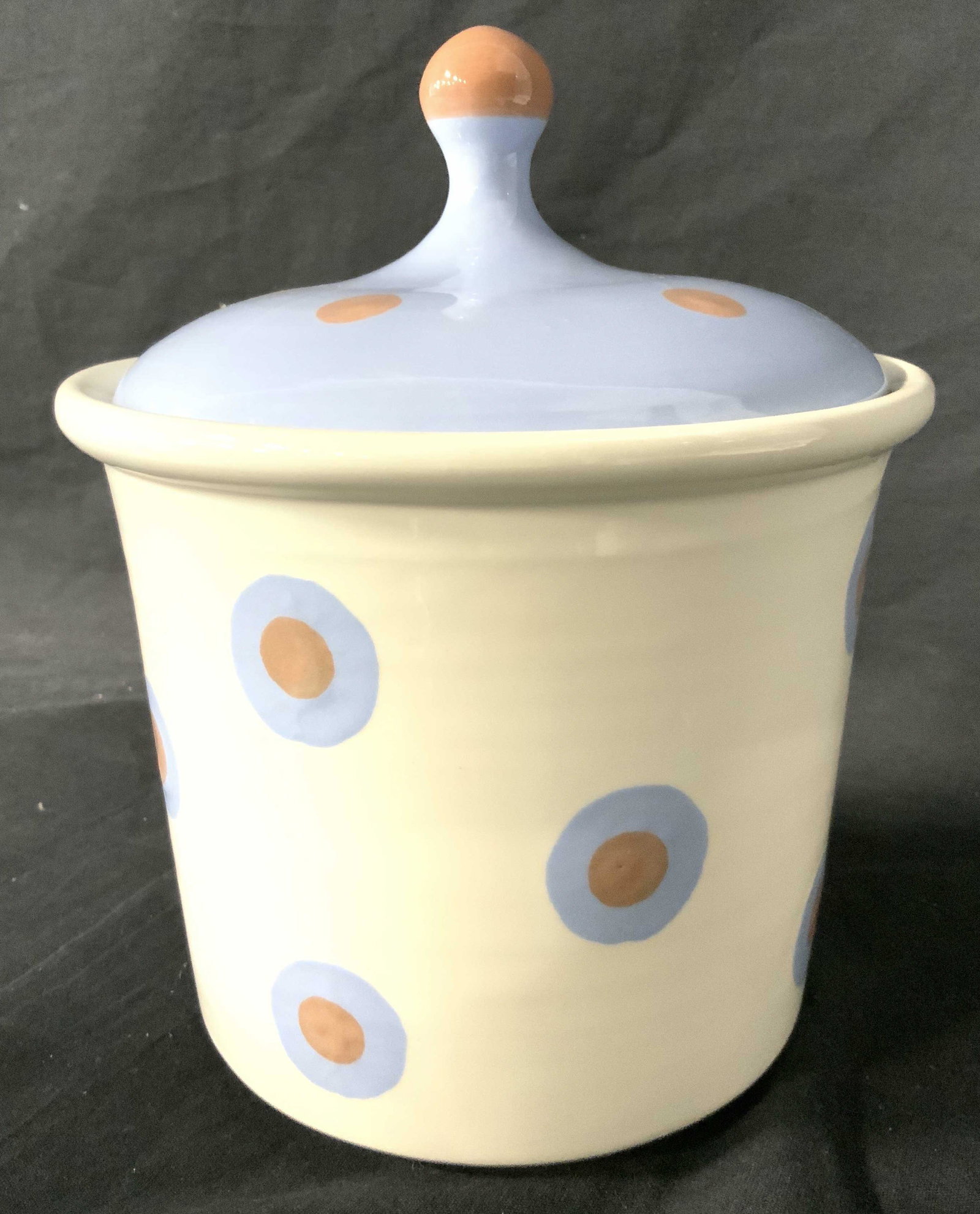 Porcelain Cookie Jar With Lid: Cookie jar is whit with pink and powder blue toned polka dot detail. Lid is powder blue with pink toned handle and dot detail. Jar has cupcake shape. Piece measures approx 9 inches tall 7.5 inches wid