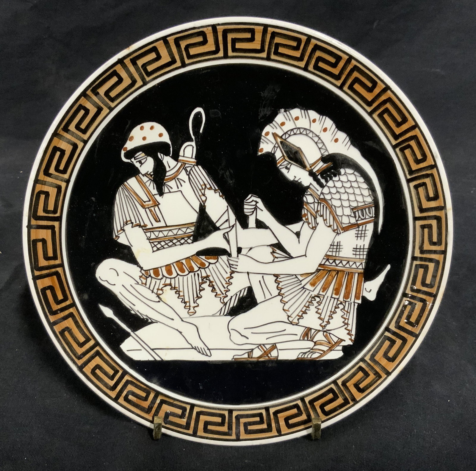 Hand Painted Greek Porcelain Plate: Hand Painted Greek porcelain plate, stamp to reverse in Greek, stamp to reverse reads ‘Handmade in Greece’, front of plate depicts two Grecian soldiers tending to a wound, Greek key design painted