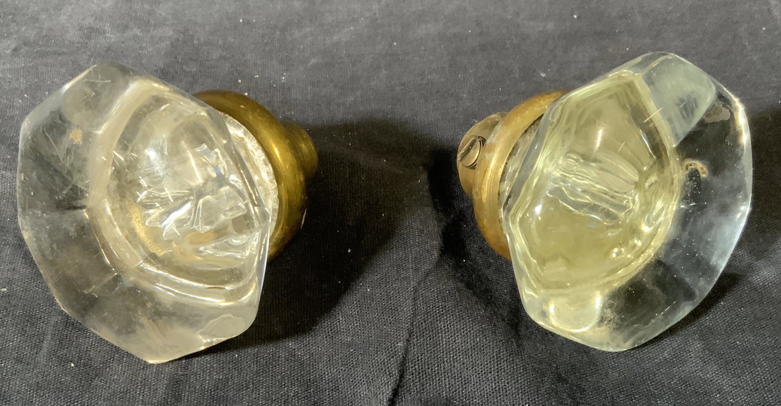Two Glass Doorknobs: Two glass door knobs, both have gold toned metal knob roses, made of a clear glass with an impression to the interior of the pieces, both measure approximately 2.25 inches in diameter on the handle an