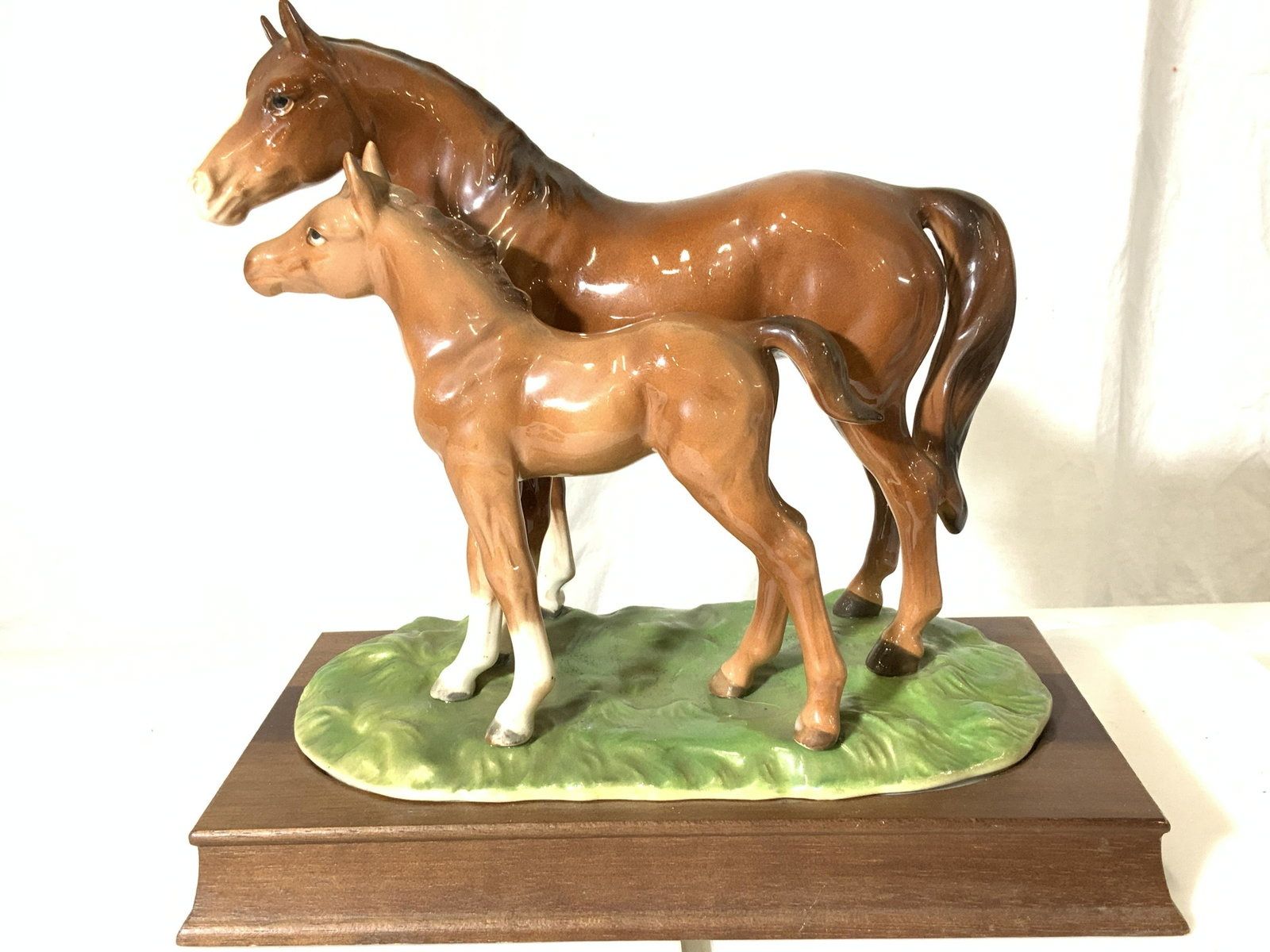 Porcelain Horse & Pony Statue on Wood Base: Hand painted and glazed horses resting on grass, porcelain figural on wood stand. No marks. walnut wood stand. Measures 9 x 5 in. Ht 9 in. Horses, porcelain horse figural, country home decor and acces