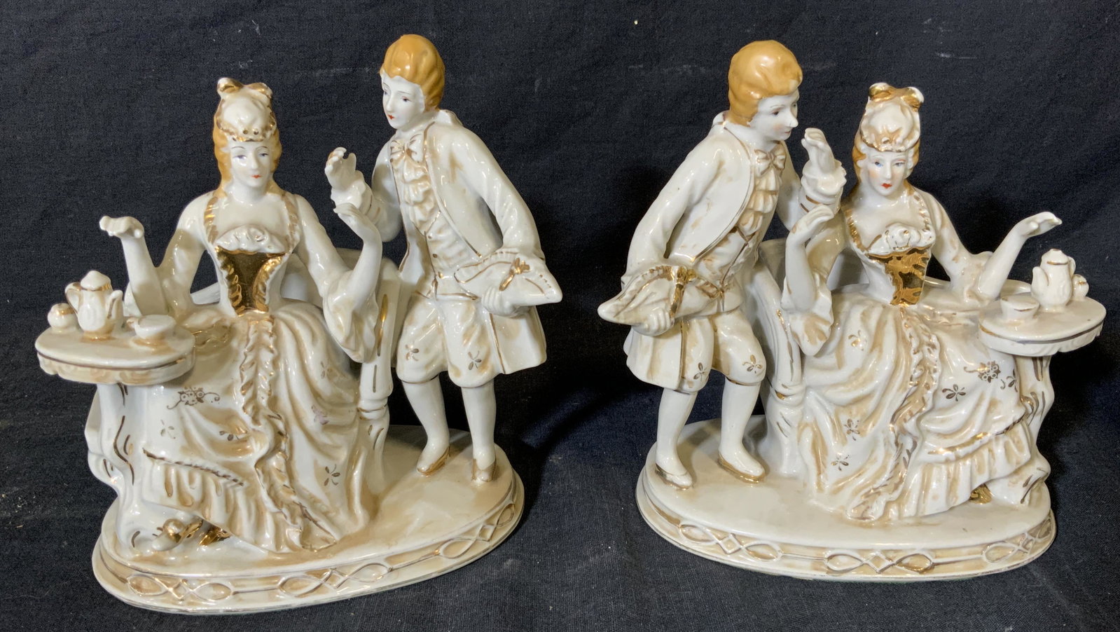 Pair French Rococo Style Porcelain Figurines: Pair French rococo style porcelain figurines, neither have any apparent inscriptions or markings, both depict a woman in a dress seated with tea with a man to her side, both are only lightly painted w