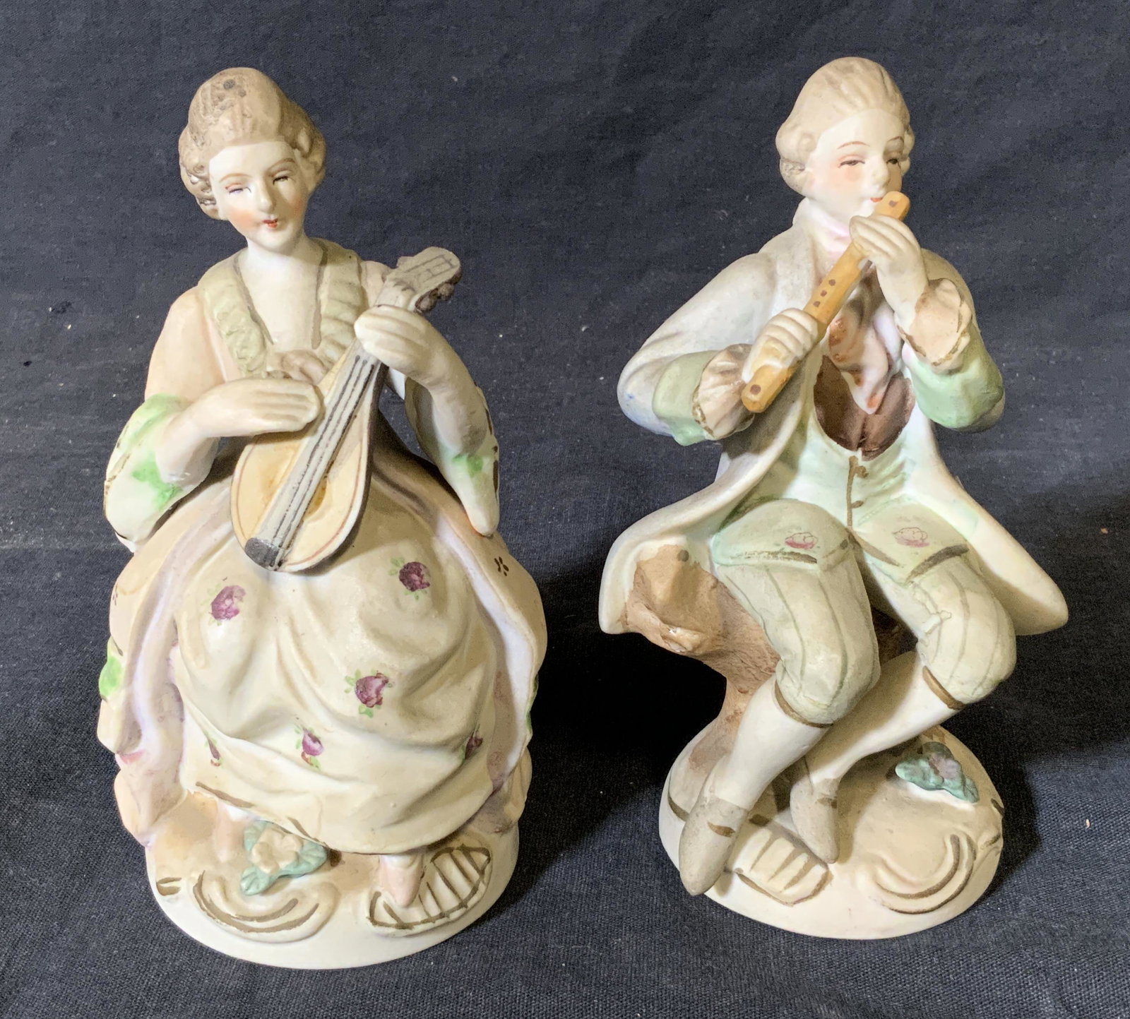 Pair Japanese Porcelain Rococo Style Figurines: Pair Japanese porcelain rococo style figurines, undersides of figurines read ‘Made in Occupied Japan’ and ‘Hand Painted Japan’, first figural depicts a man seated and playing a flute the secon